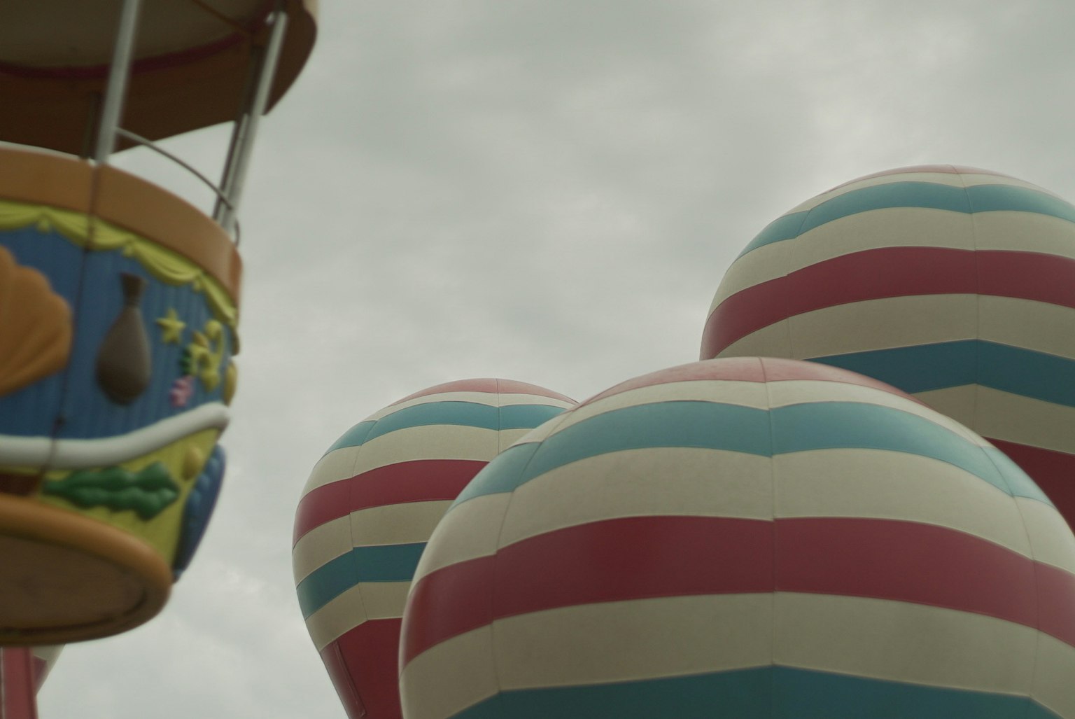 Colorful striped hot air balloons partially visible against a cloudy sky