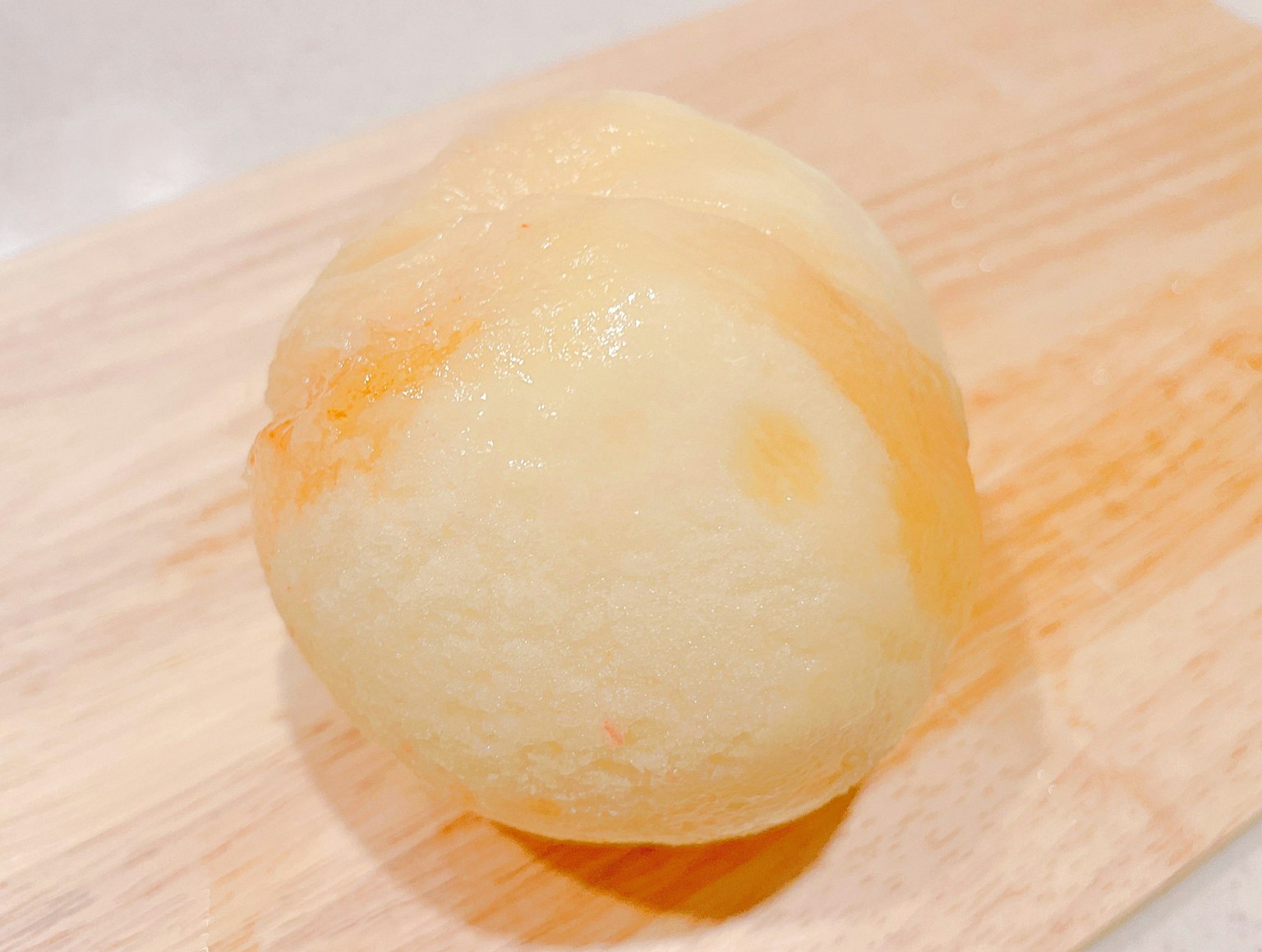 Peeled white peach resting on a wooden board