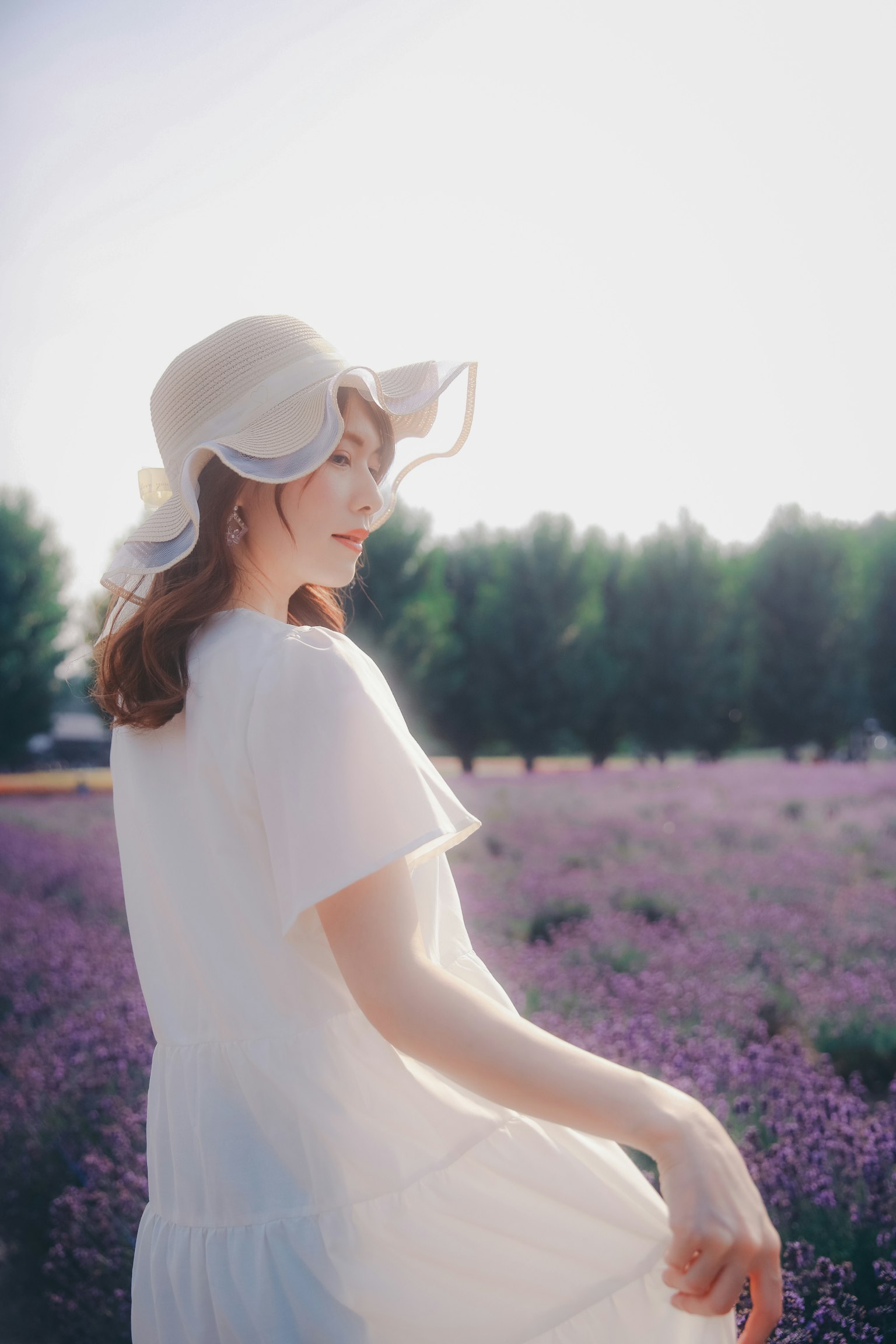 Una mujer con un vestido blanco se gira en un campo de lavanda con luz suave