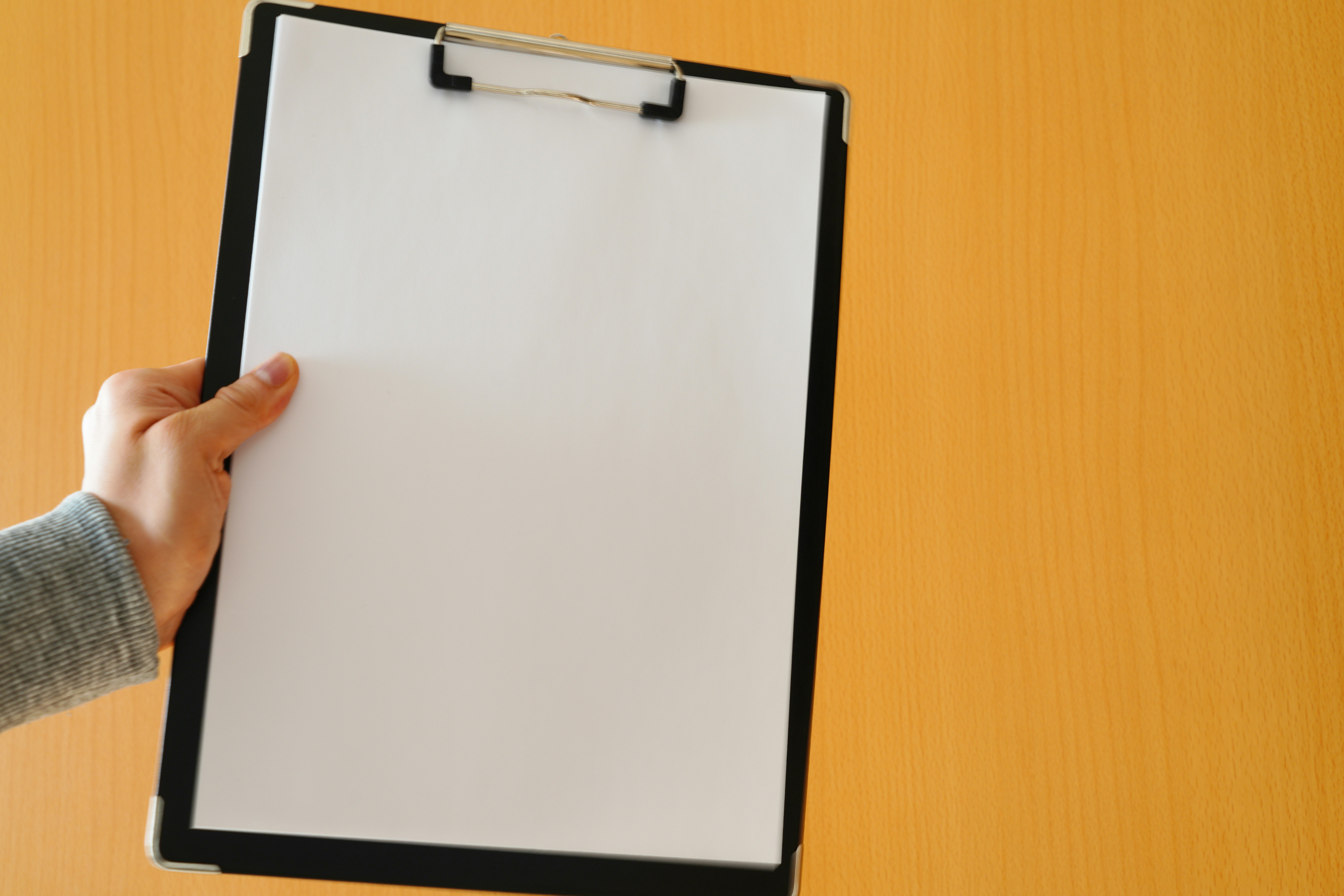 hand holding a clipboard with blank paper