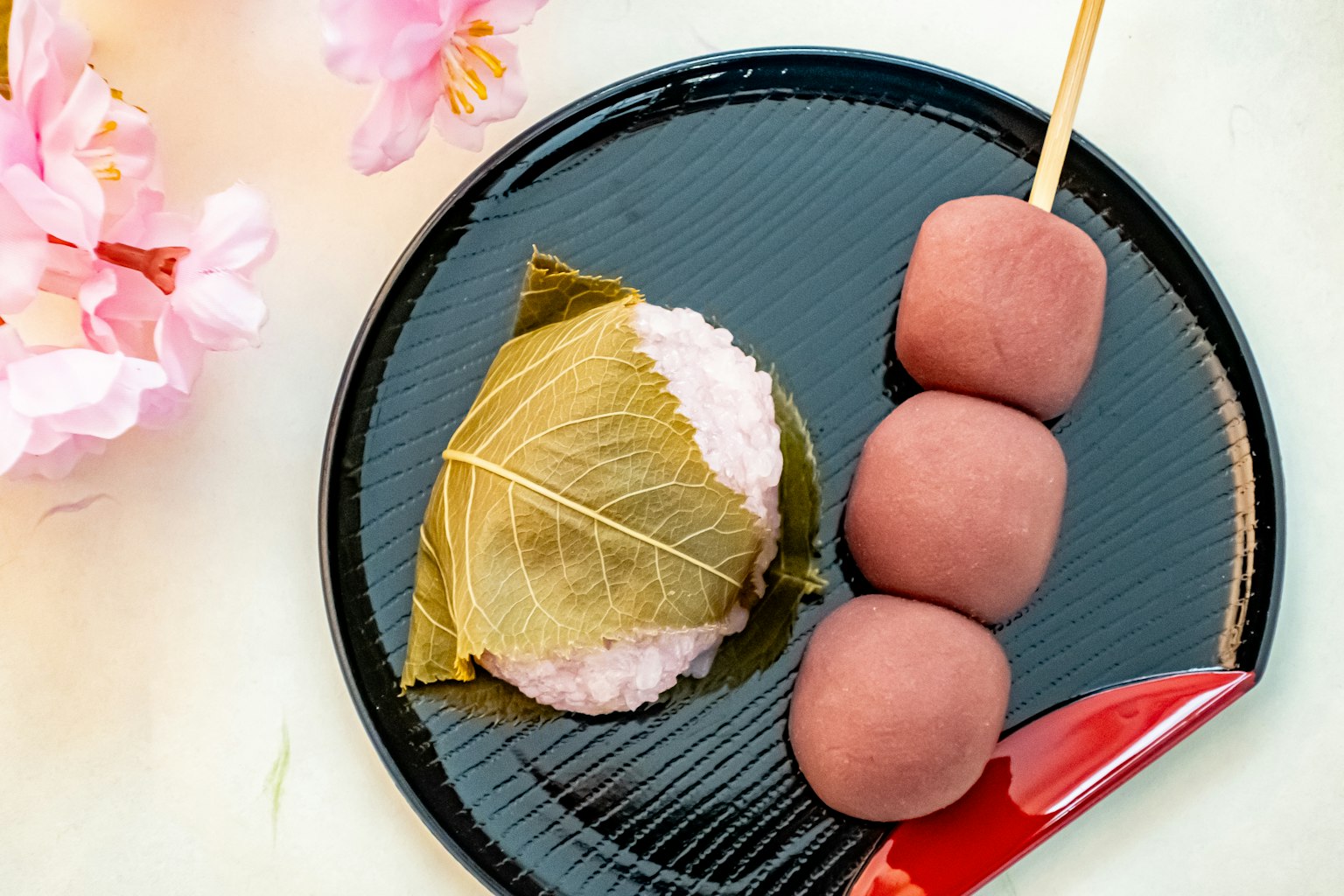 검은 접시에 올려진 일본 과자와 벚꽃잎