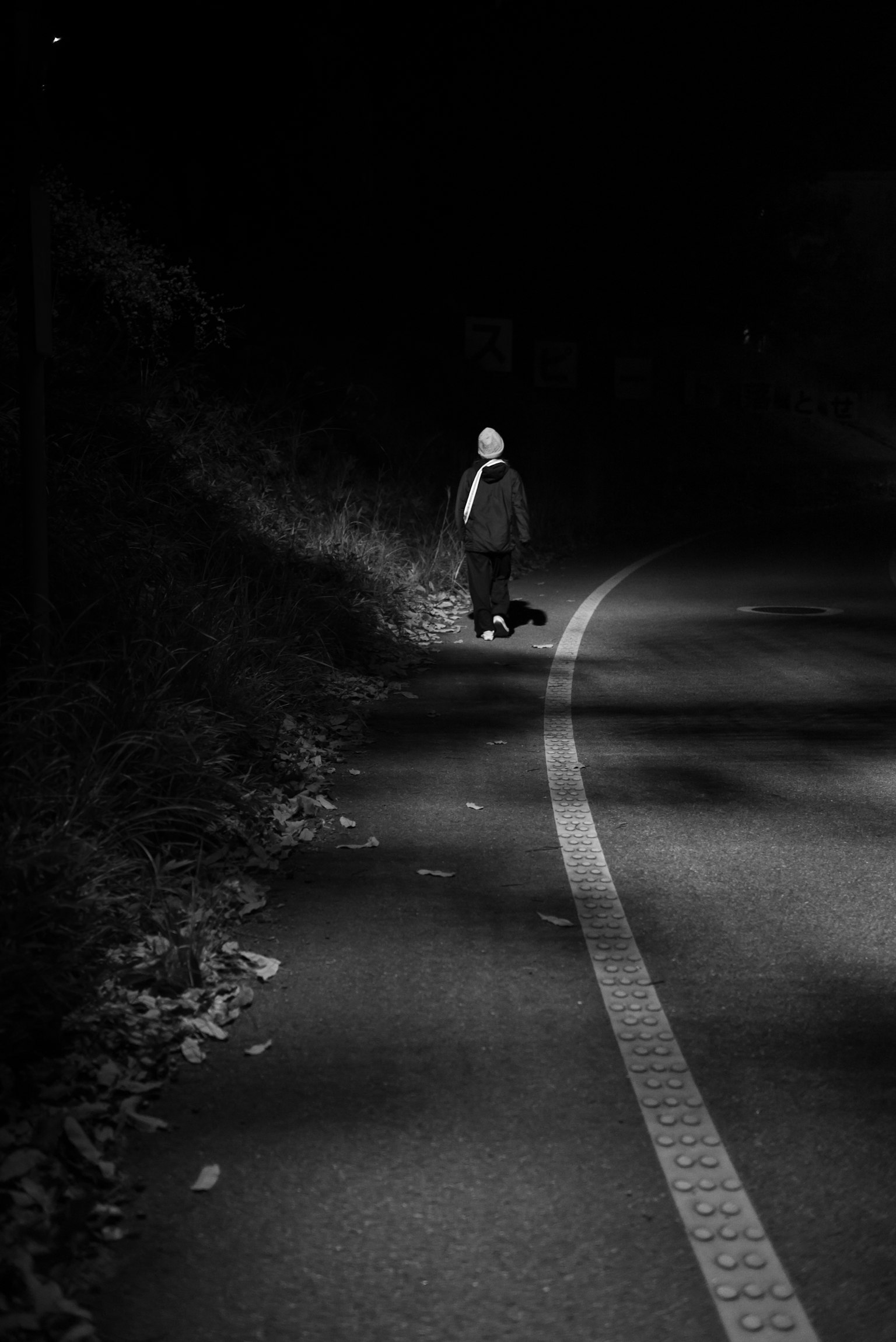 夜間在路上行走的人的黑白照片