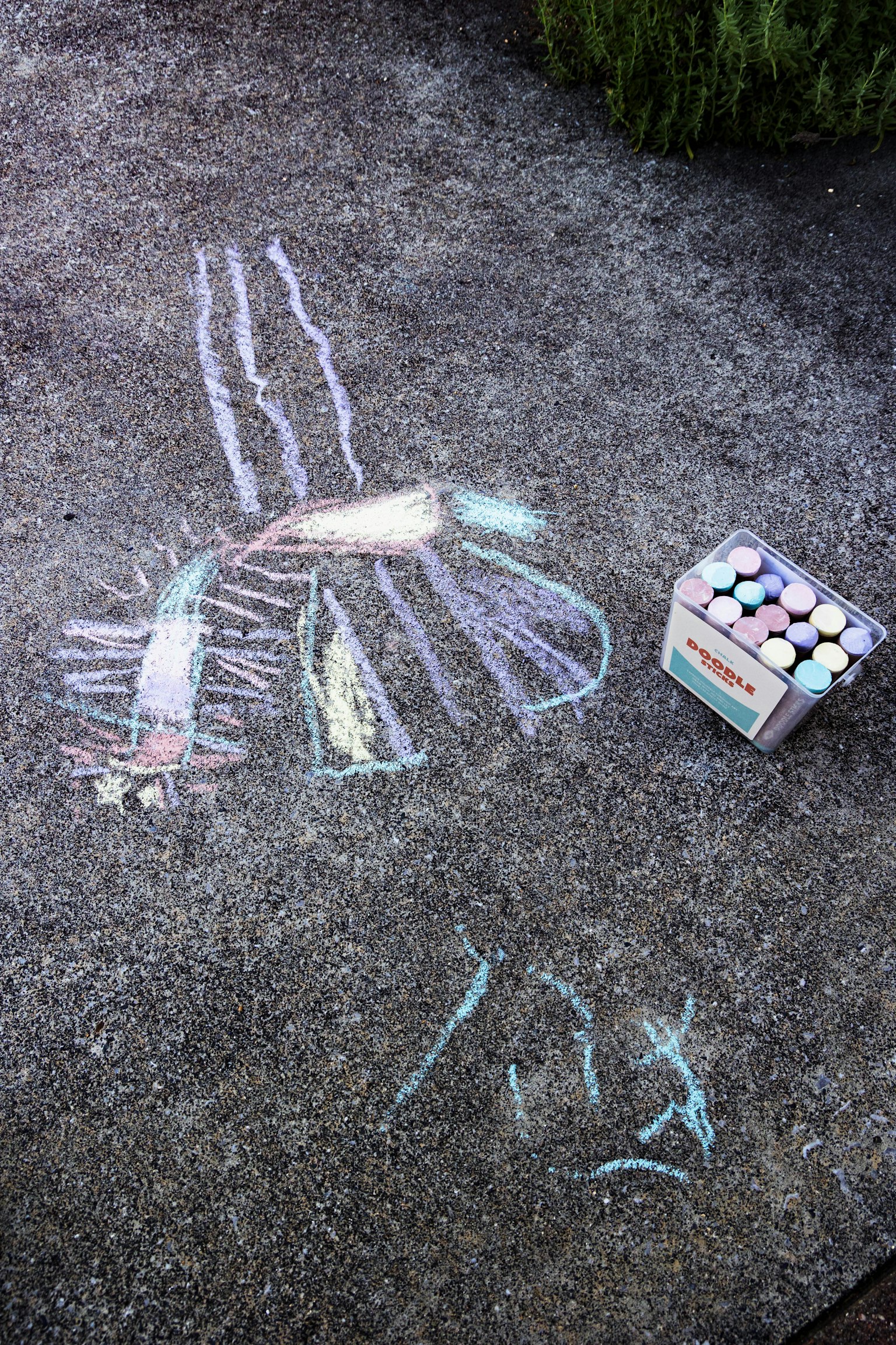 地面に描かれたカラフルなチョークアートとチョークの箱