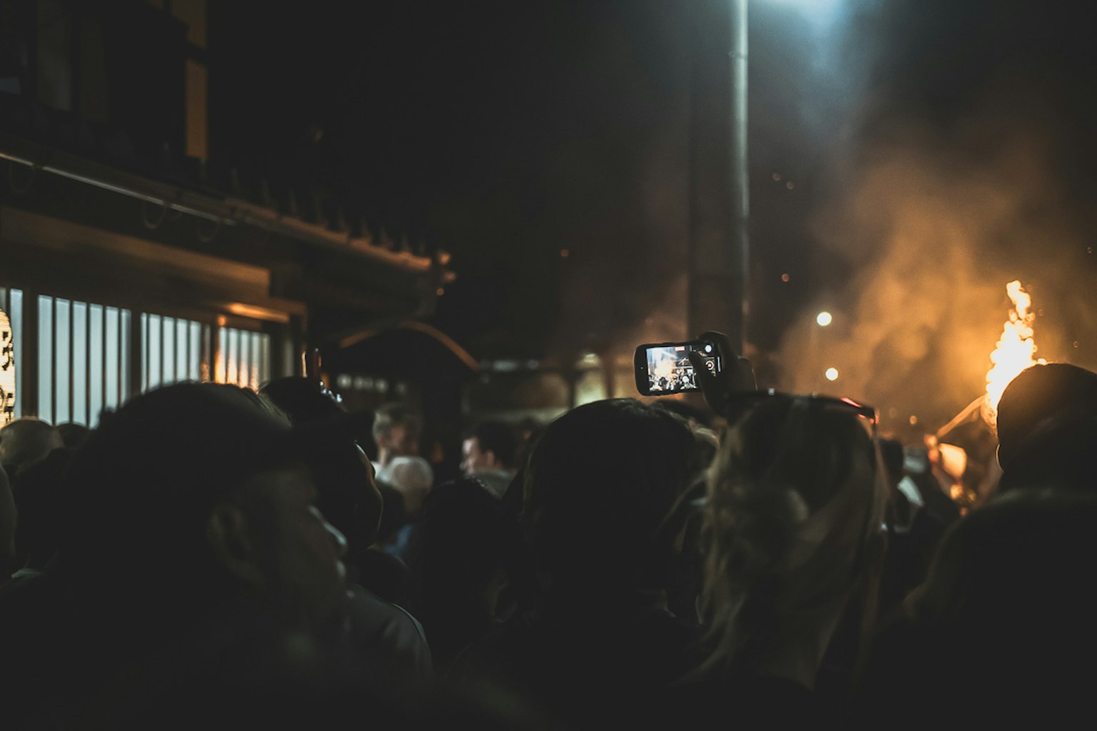 Menschenmenge genießt ein Nachtfestival mit Flammen im Hintergrund