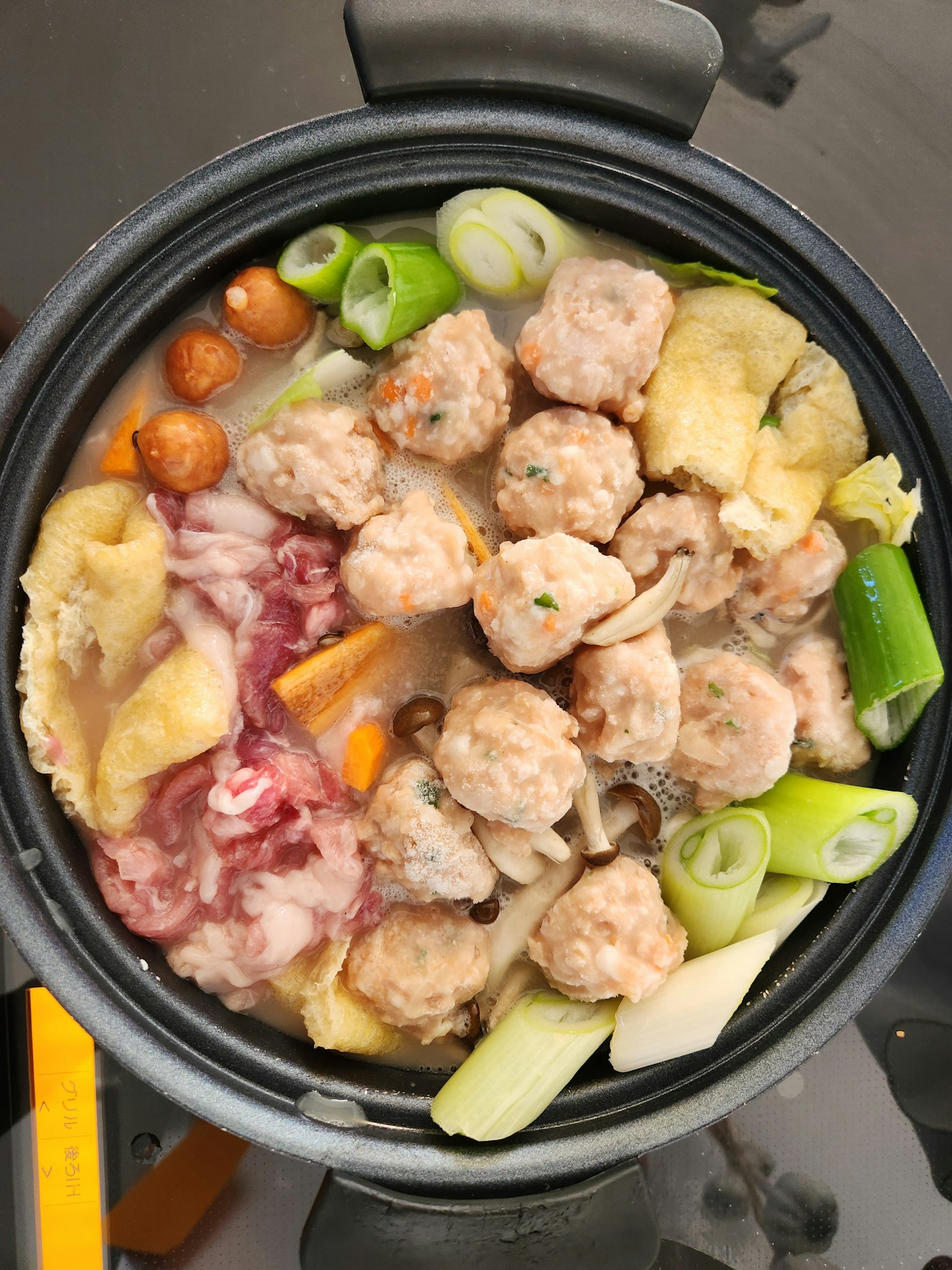 锅中装满了肉丸、蔬菜和青葱