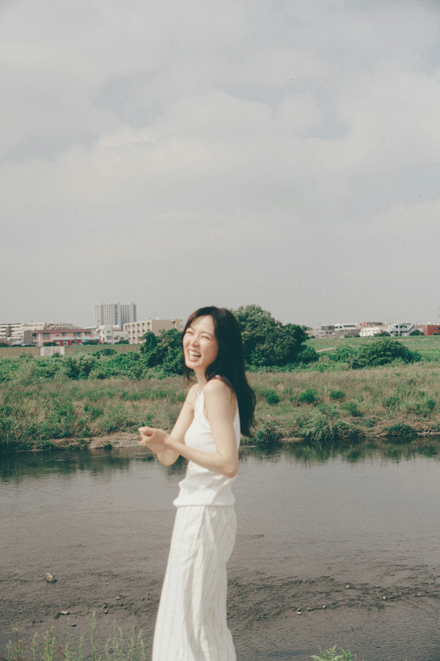 Una donna in abito bianco che sorride vicino al fiume