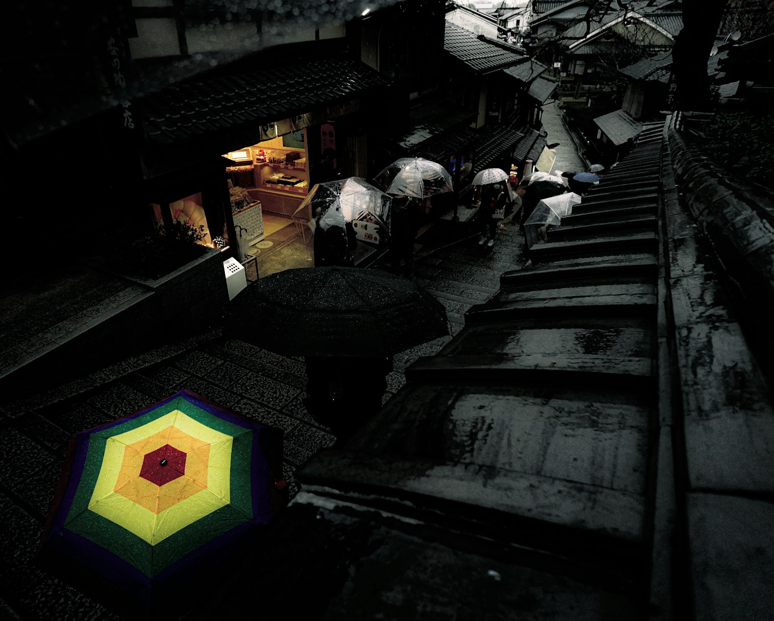 Un paraguas hexagonal colorido en una escena de calle poco iluminada