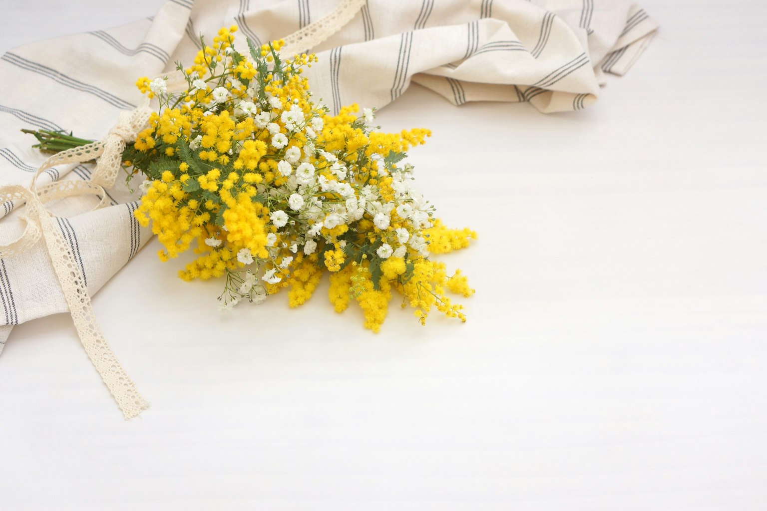 Un ramo de mimosa amarilla y flores blancas sobre una tela