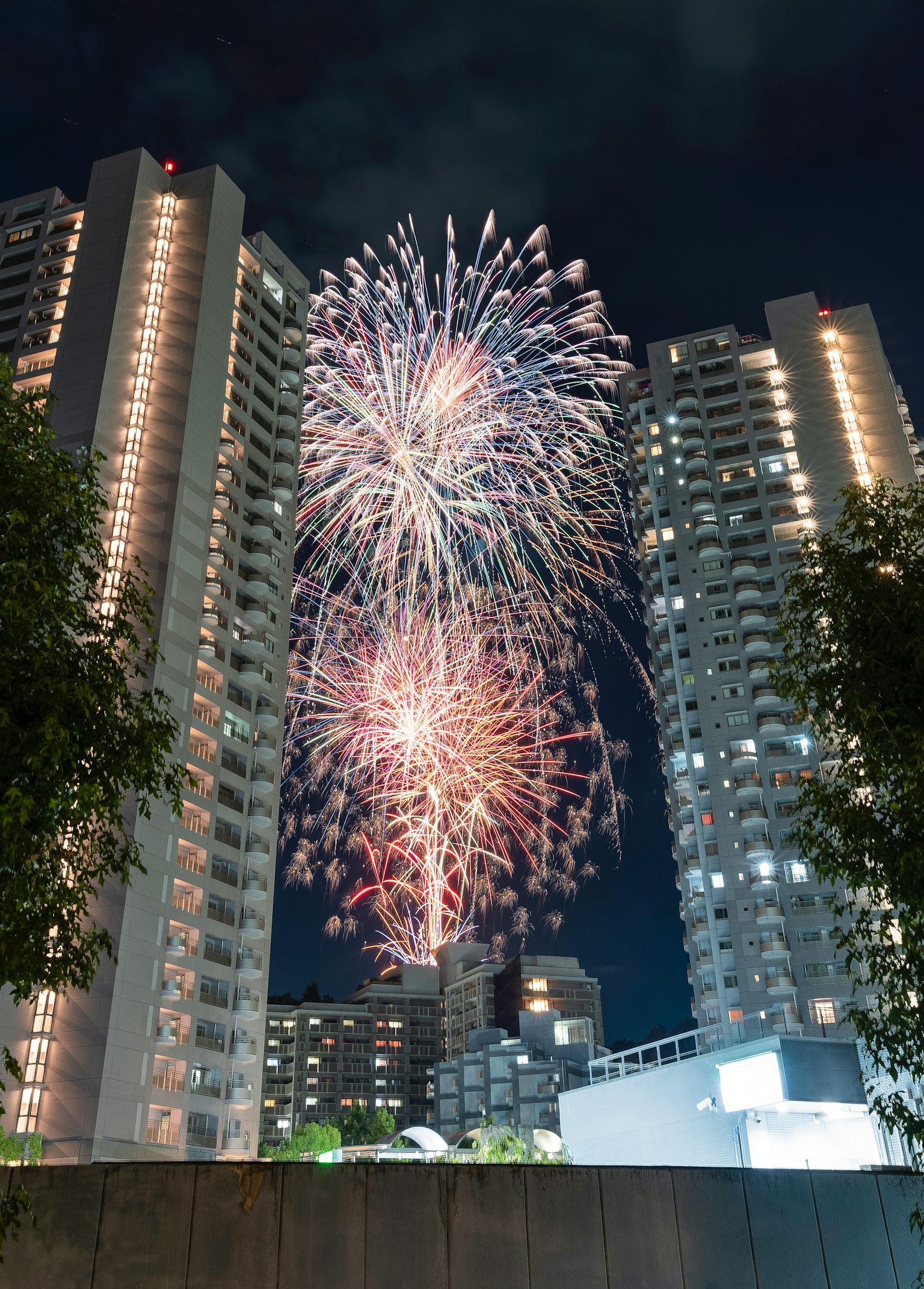 Des feux d'artifice éclatant dans le ciel nocturne entre des immeubles