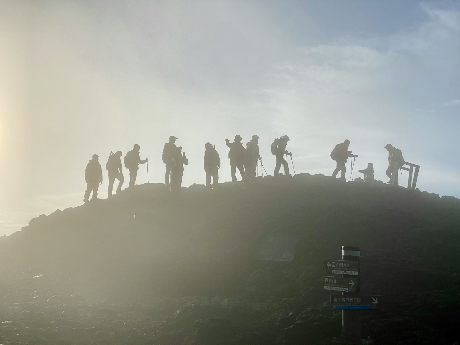 Siluet pendaki berdiri di puncak gunung dalam kabut