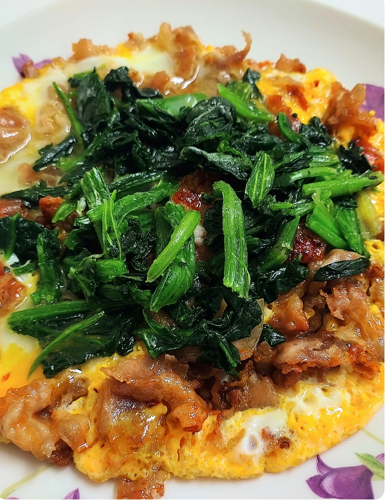 ไข่เจียวท็อปด้วยผักและเนื้อสัตว์เสิร์ฟในจานลายดอกไม้