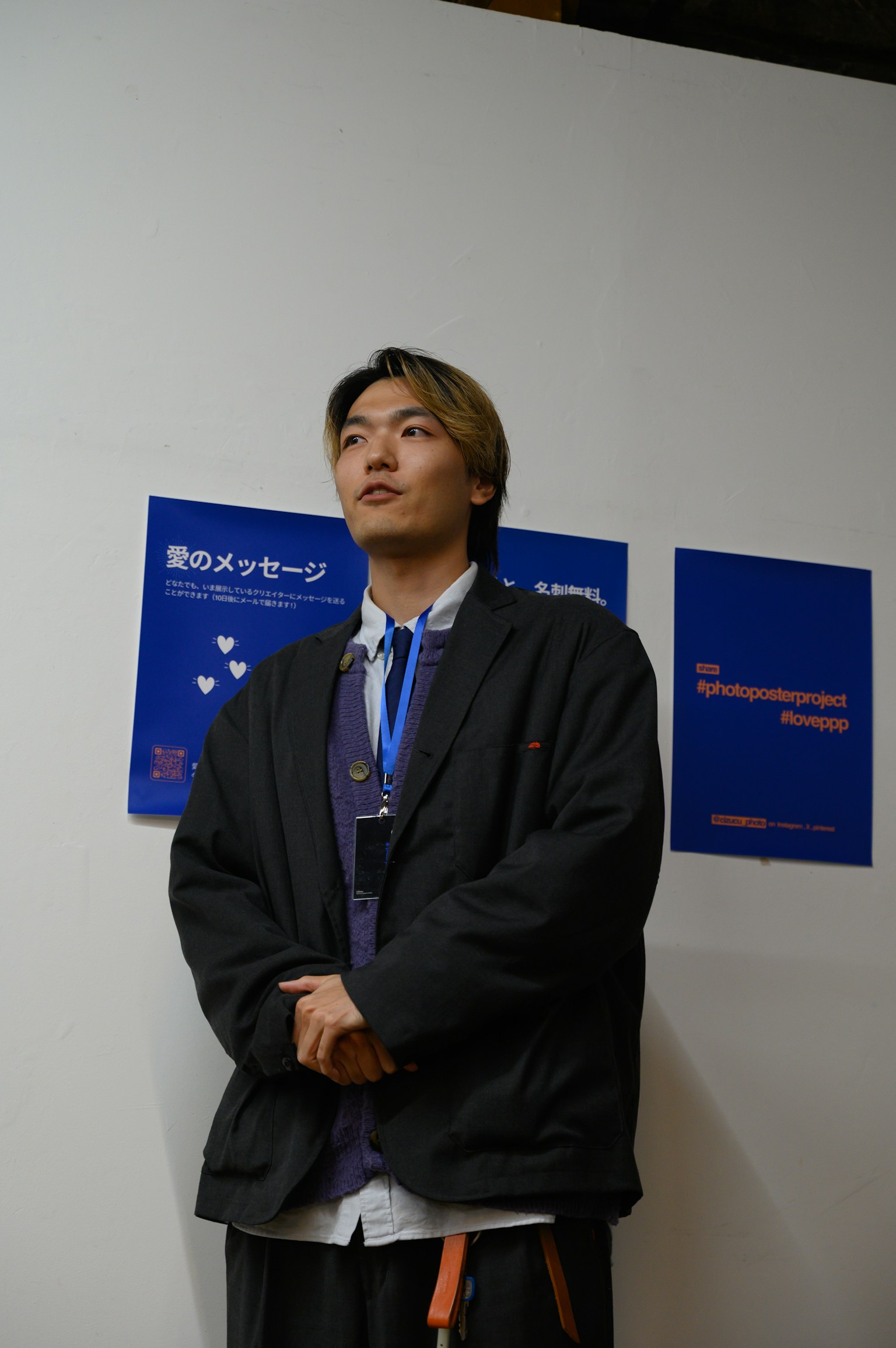 A man wearing a black jacket standing in front of blue posters