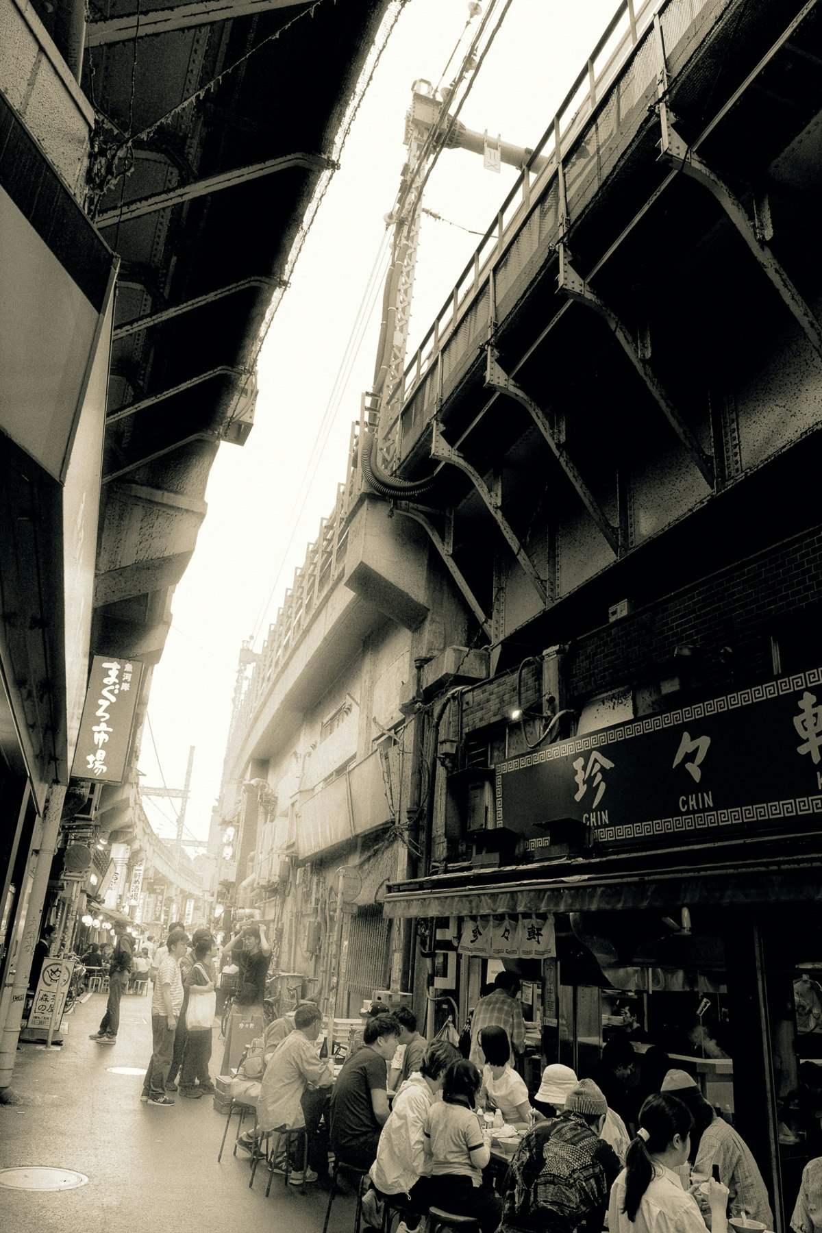 路地のアーケード下で人々が並ぶ香港の商店街の風景