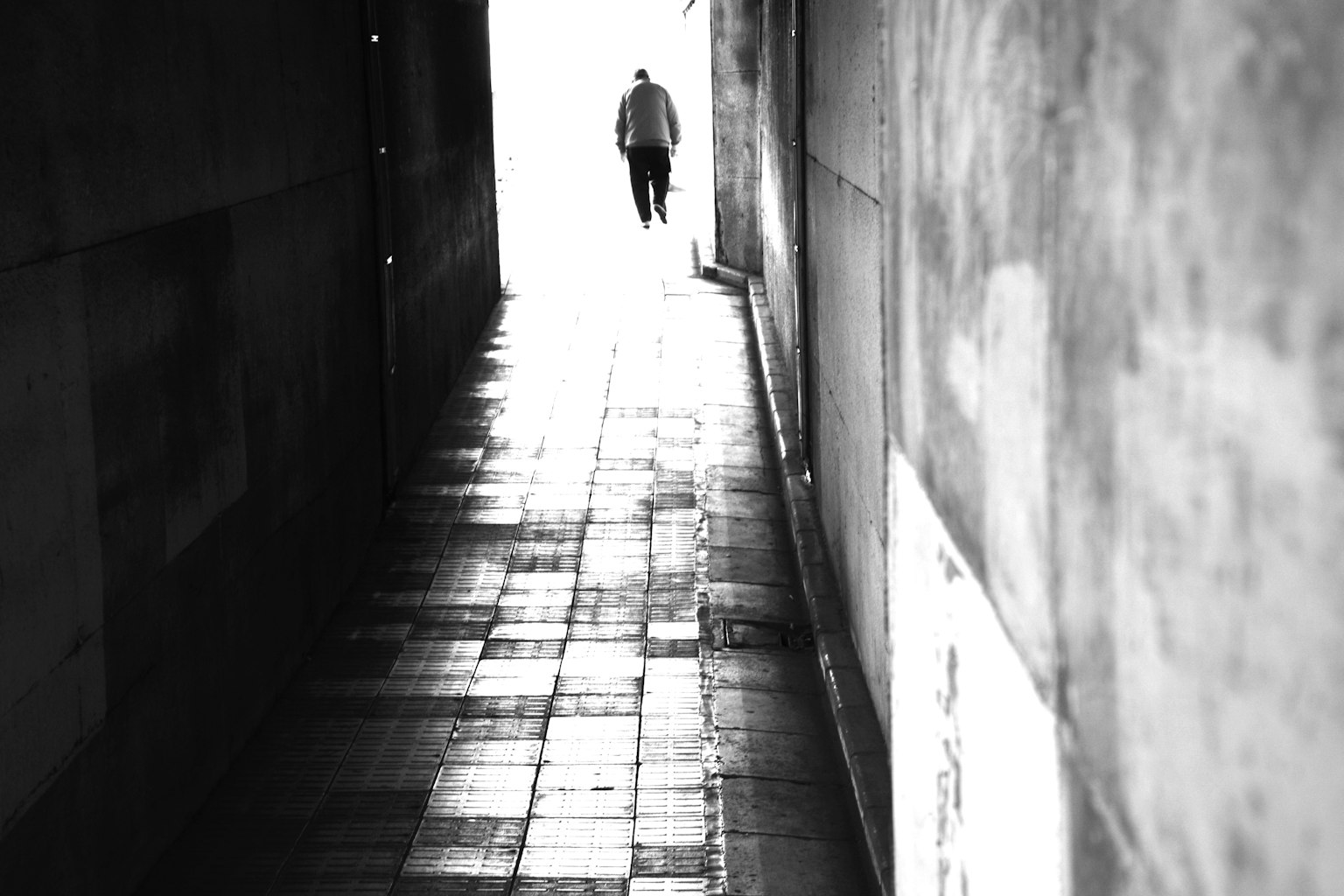 eine Person, die in einer dunklen Gasse zu hellem Licht geht