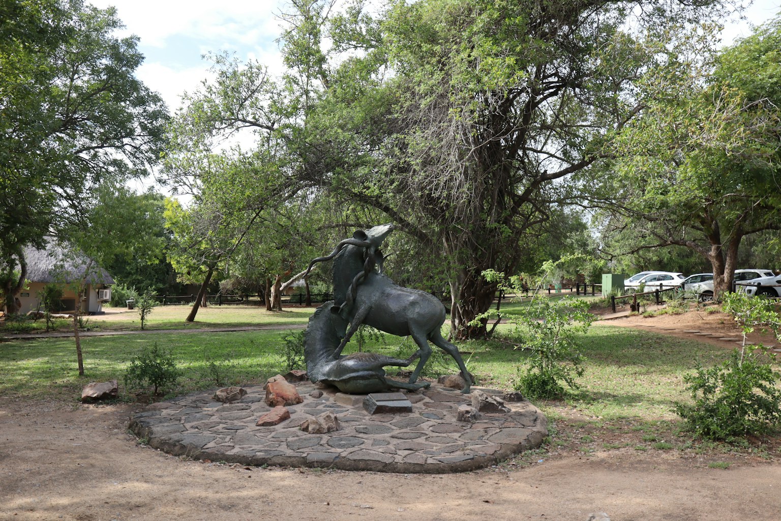 Una scultura blu di un cavallo inarcato circondata da verde lussureggiante