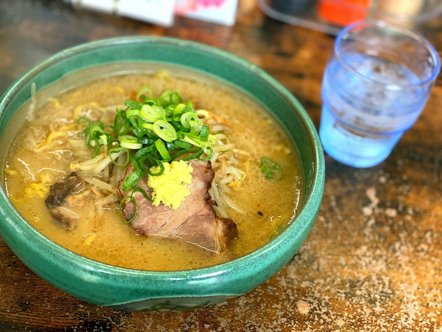 Soupe de ramen dans un bol vert garnie d'oignons verts et de gingembre
