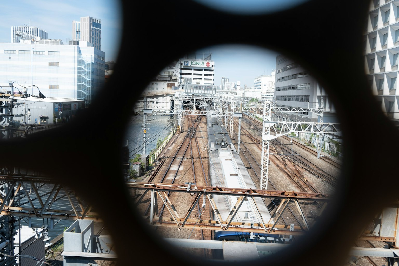 Urban landscape featuring railway tracks viewed through a circular opening