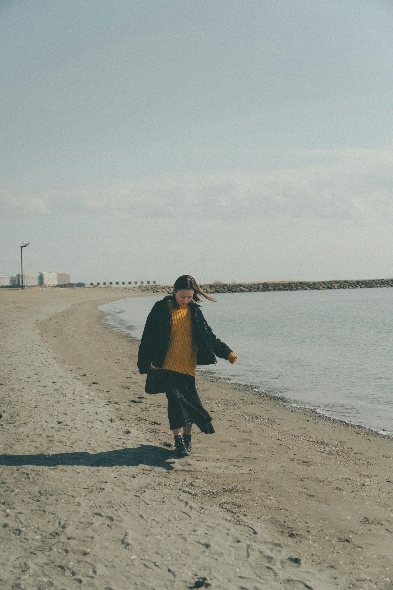 Person walking on a beach with calm water