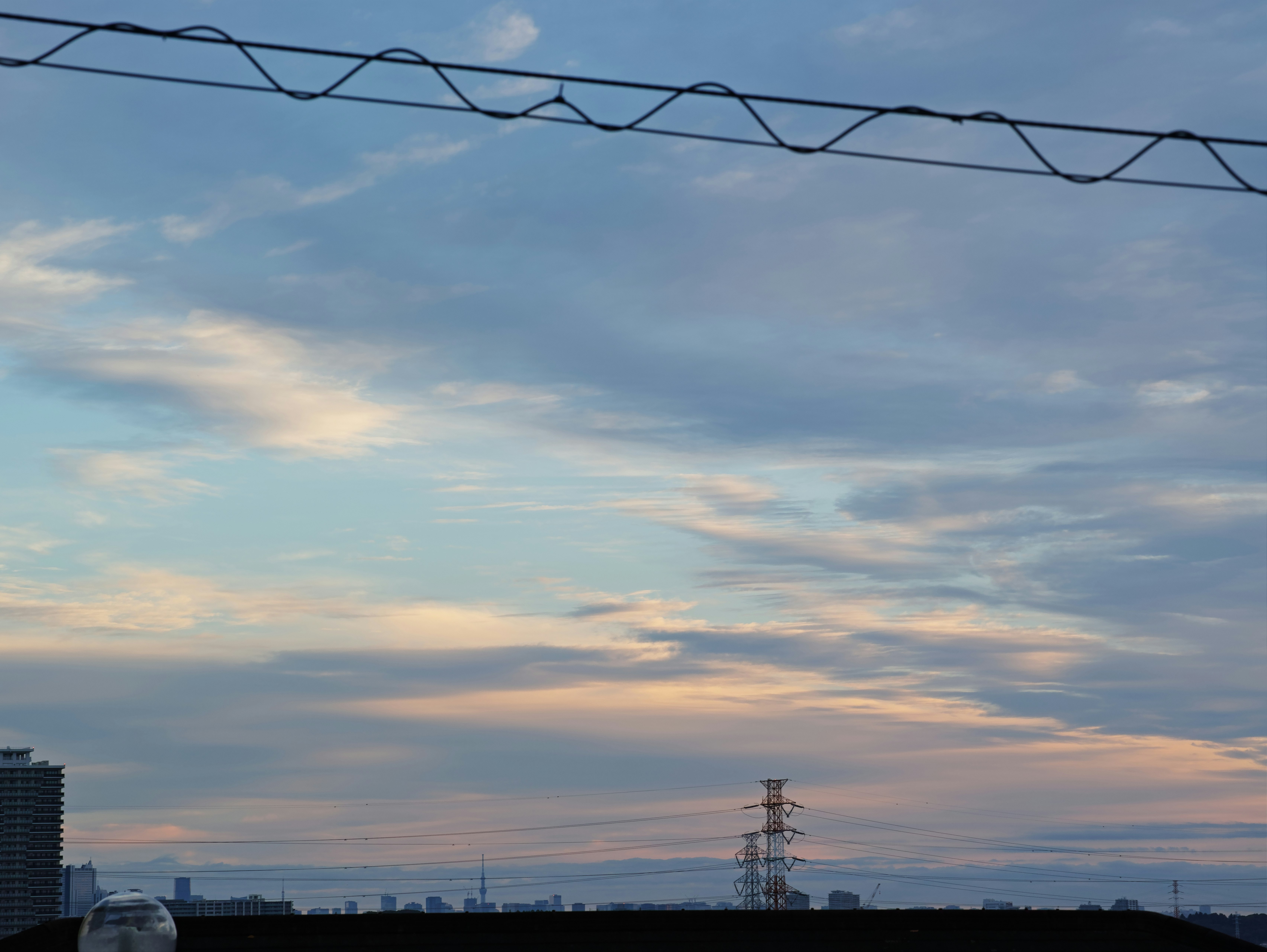 空に広がる雲と夕焼けのグラデーション、送電線のシルエット