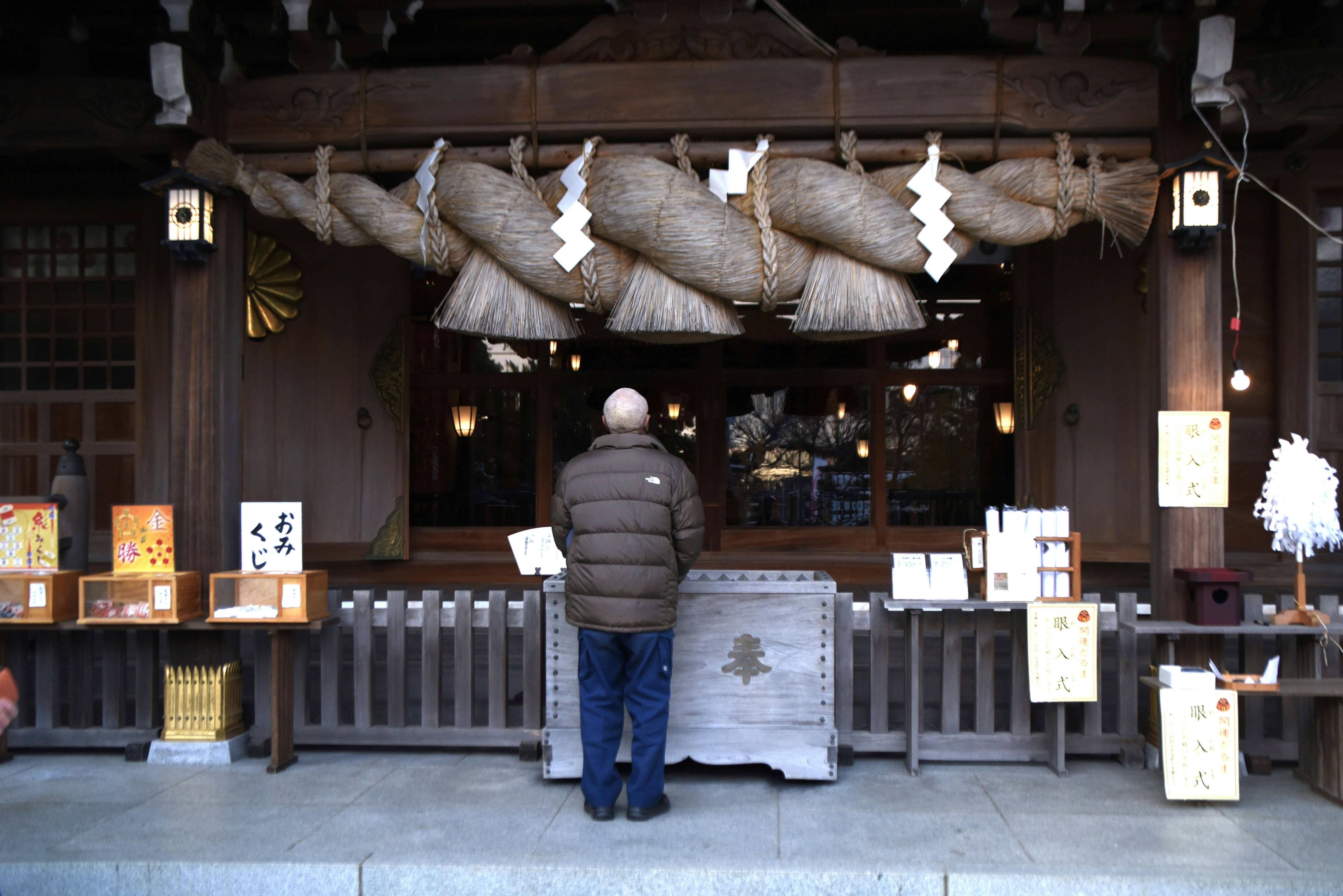 大磯六所神社達摩市，陳列的護身符與背影參拜者