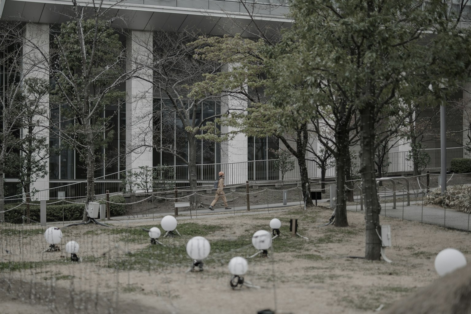 Un giardino davanti a un edificio con lampade sferiche bianche e alberi circostanti