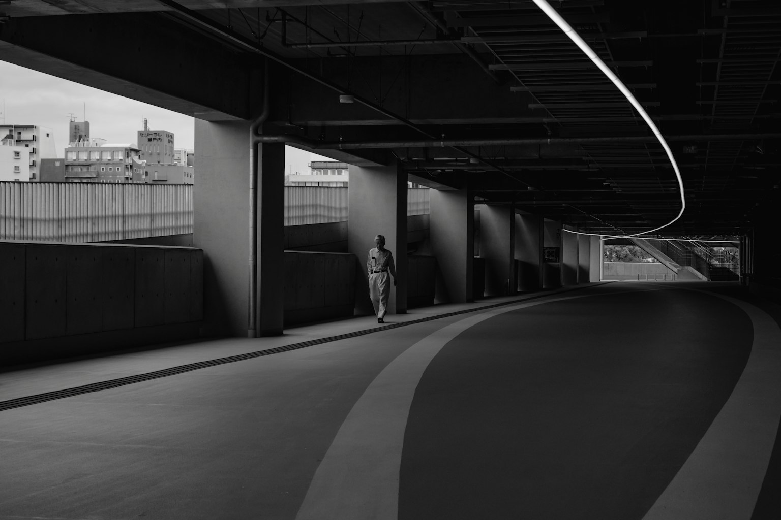 Silhouette of a person walking in a black and white tunnel with curved lines