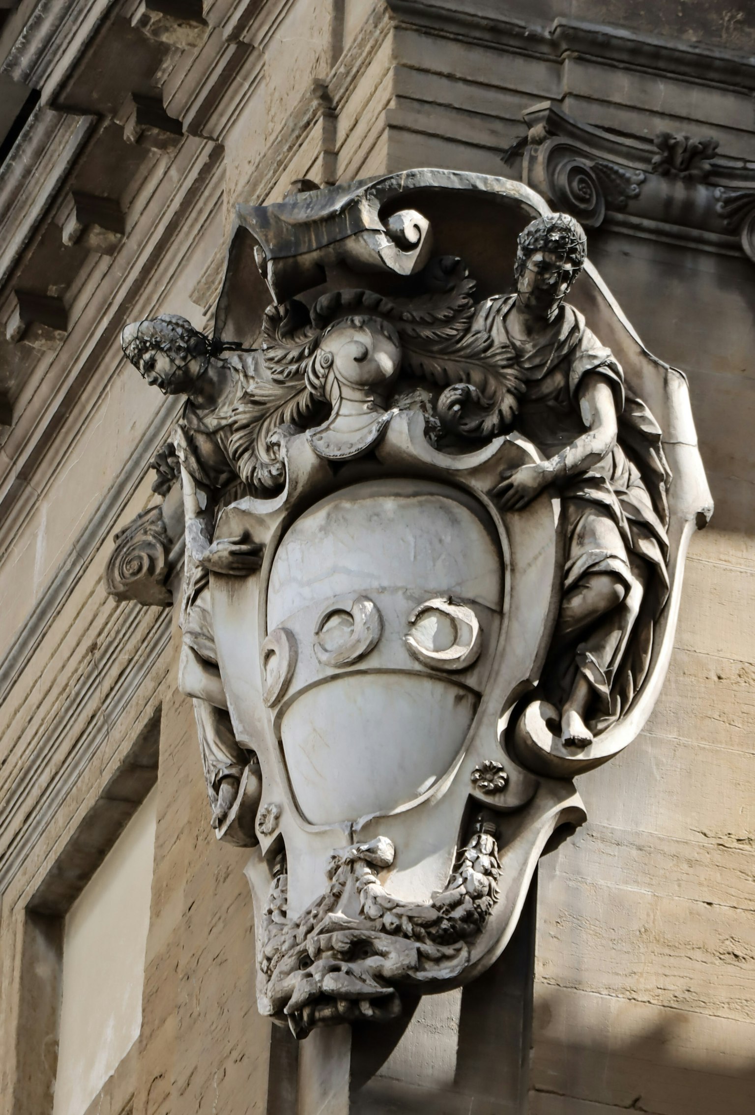 Design di scudo ornato su una colonna di edificio con figure scolpite