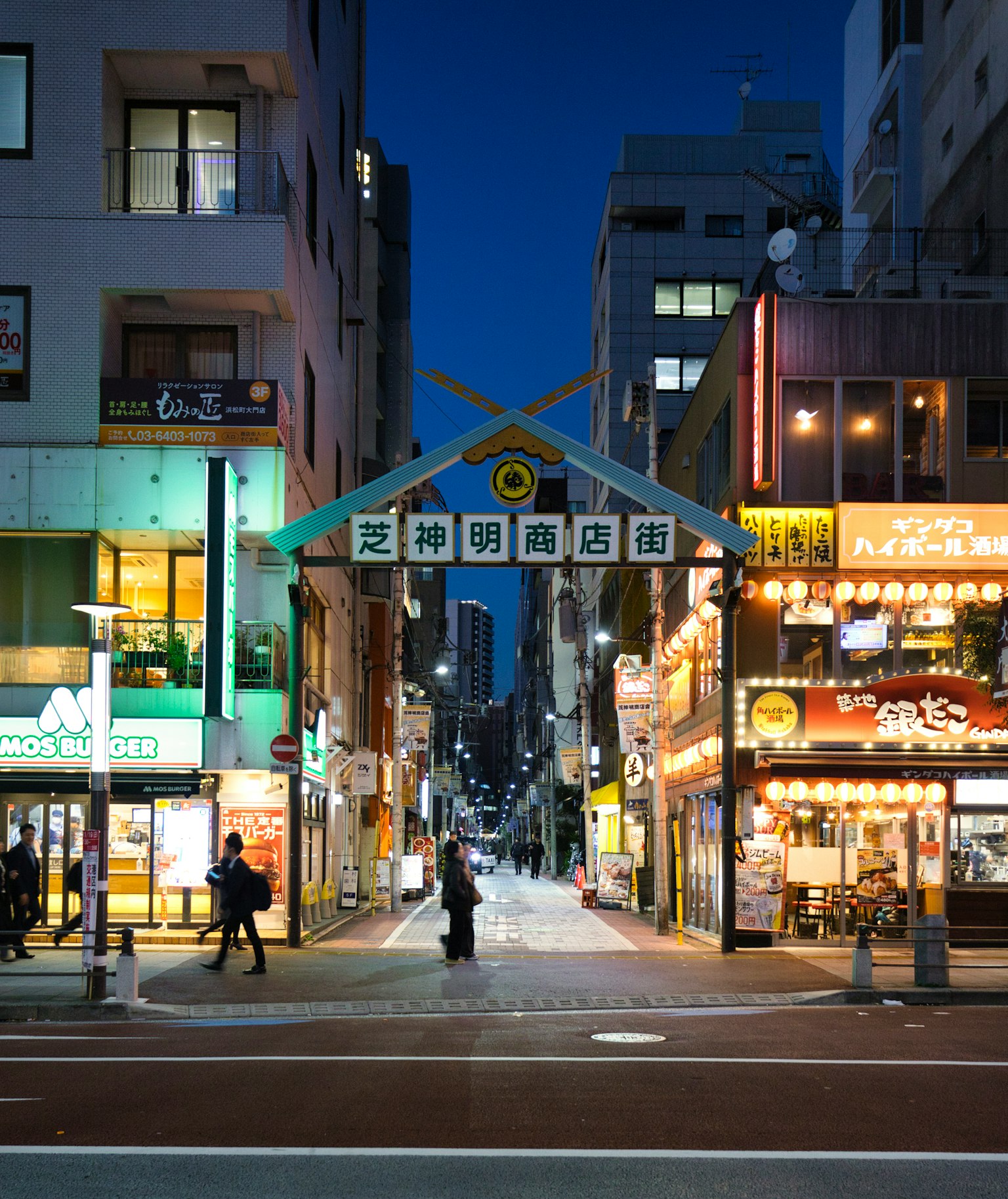 ทิวทัศน์ถนนที่มีชีวิตชีวาในตอนกลางคืนพร้อมป้ายร้านอาหารที่มีสีสัน