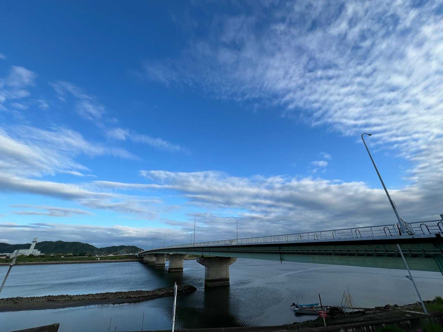 一座桥横跨在河流之上，蓝天与稀疏的云朵相映成趣
