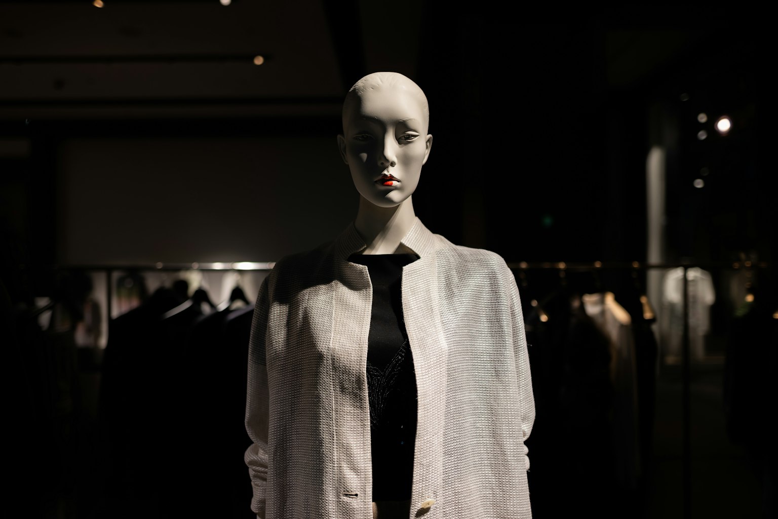 白色模特站在展示窗中穿著黑色衣服被燈光突出