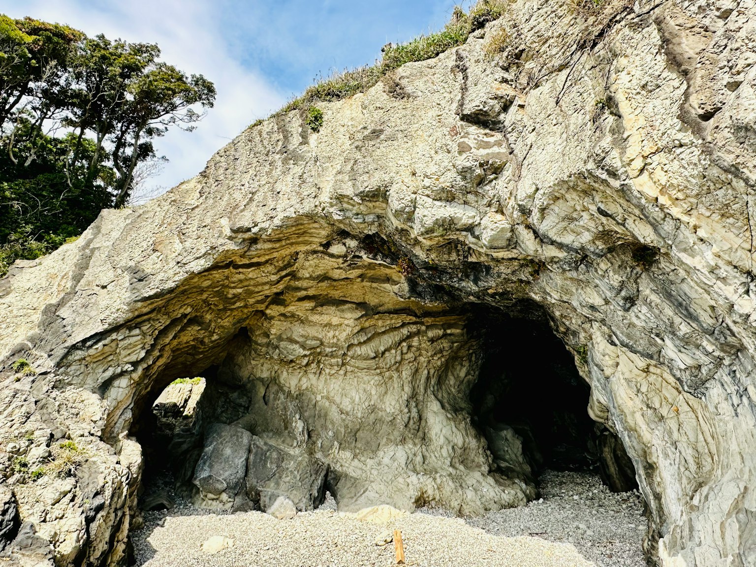 Cueva de roca con capas de piedra caliza visibles y paisaje costero