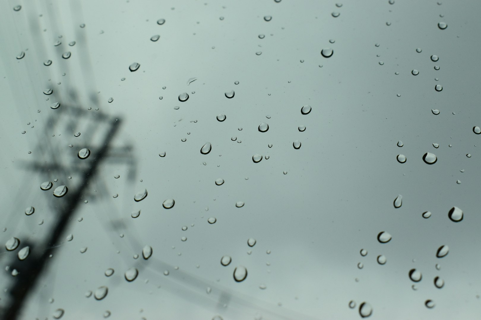 車窓に映る雨粒と電柱のある風景