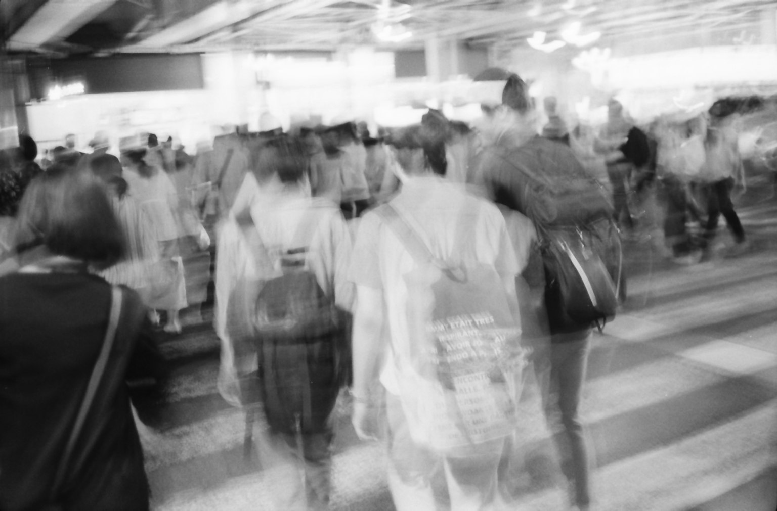 Blurred black and white image of people crossing a busy intersection
