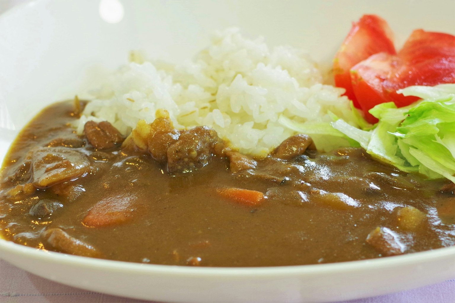 Un plato de curry servido con arroz blanco y verduras frescas