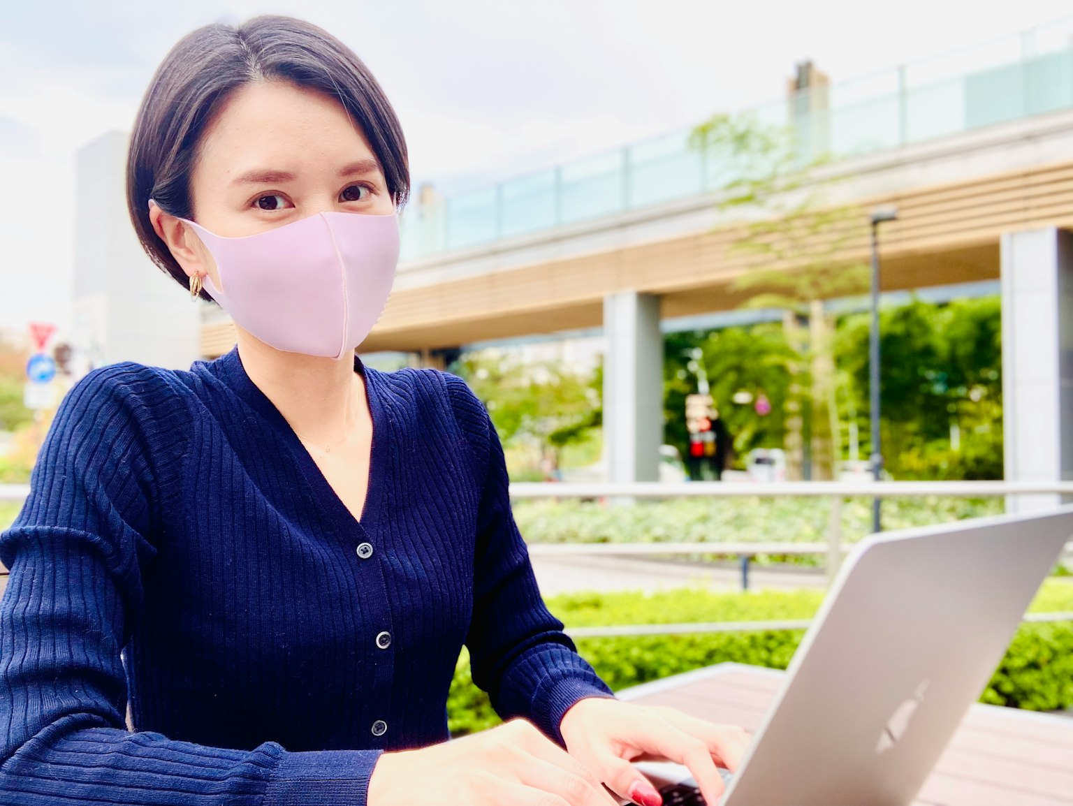 야외에서 노트북을 사용하는 여성 마스크 착용 녹색 배경