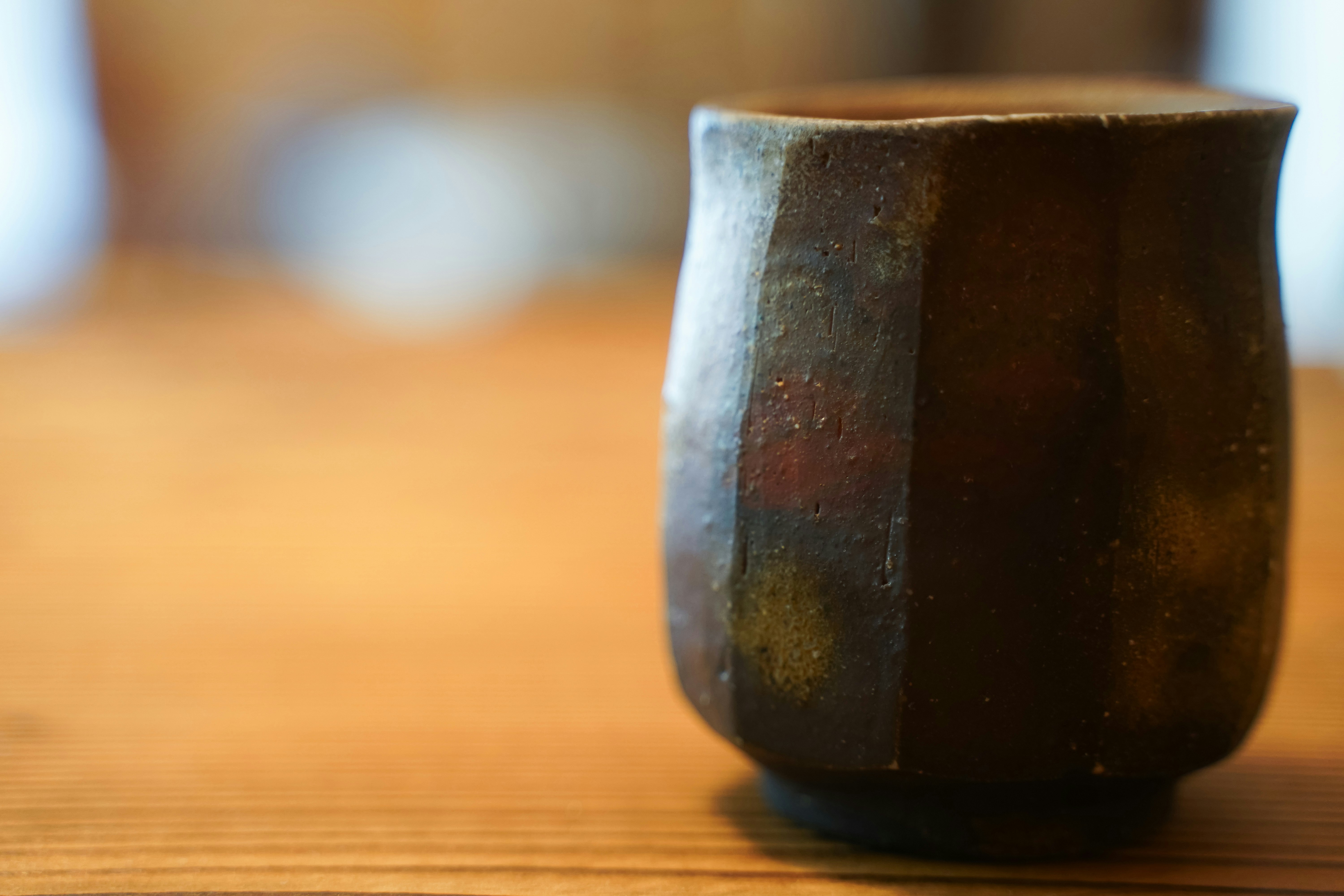 木のテーブルに置かれた黒い陶器の湯呑み