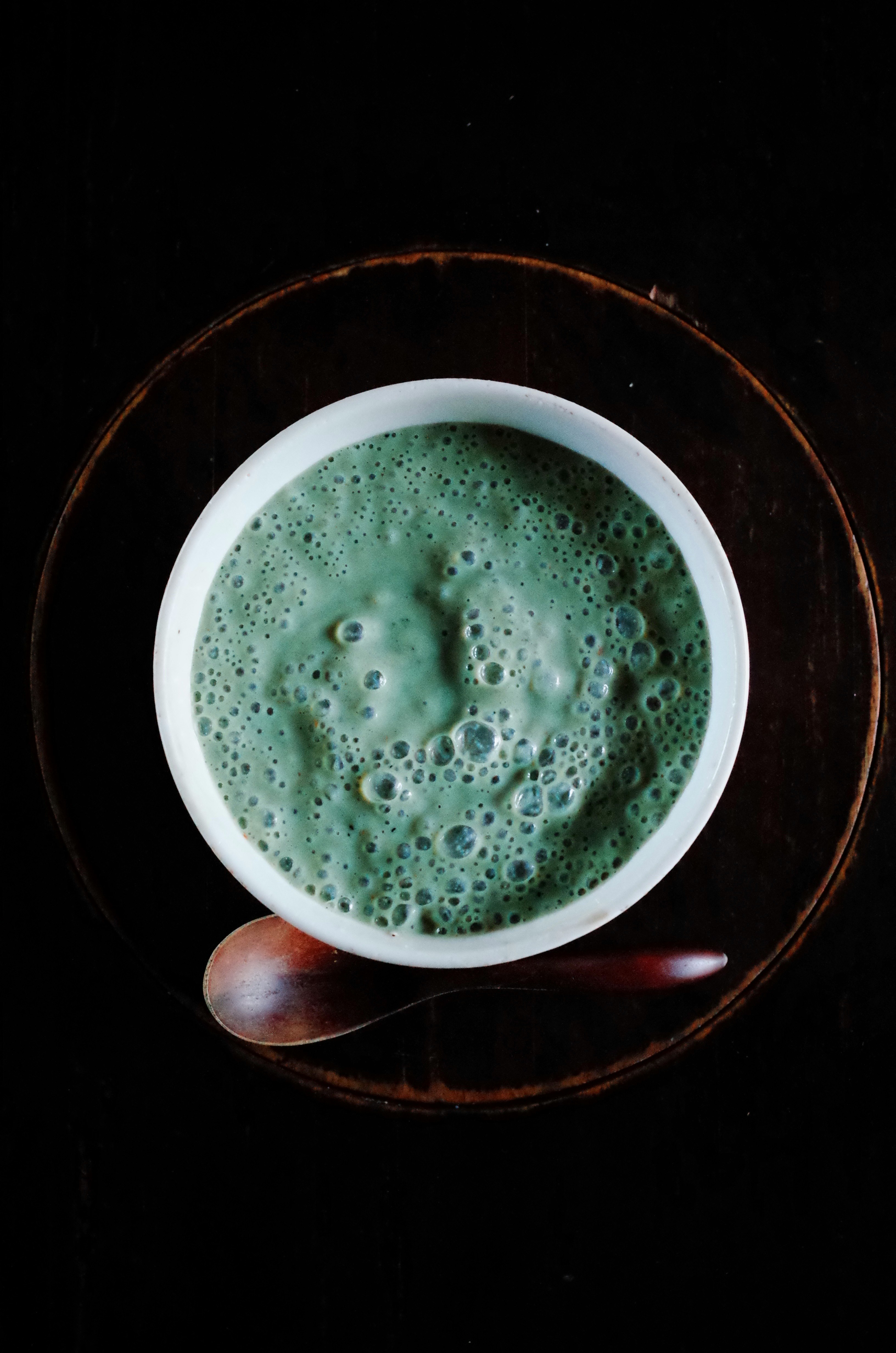 foam-topped matcha latte in a white cup on a dark background