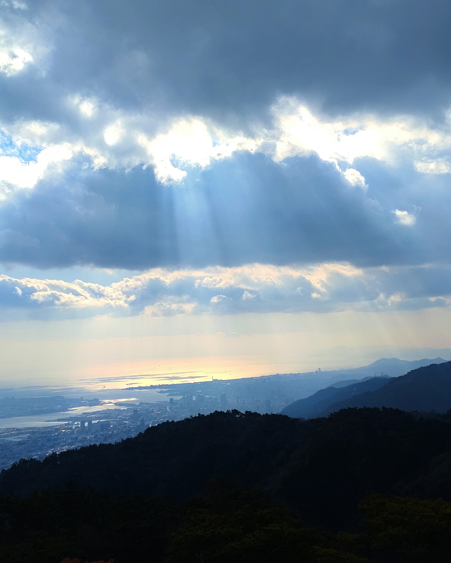 Luce del sole che filtra attraverso le nuvole su montagne e acqua