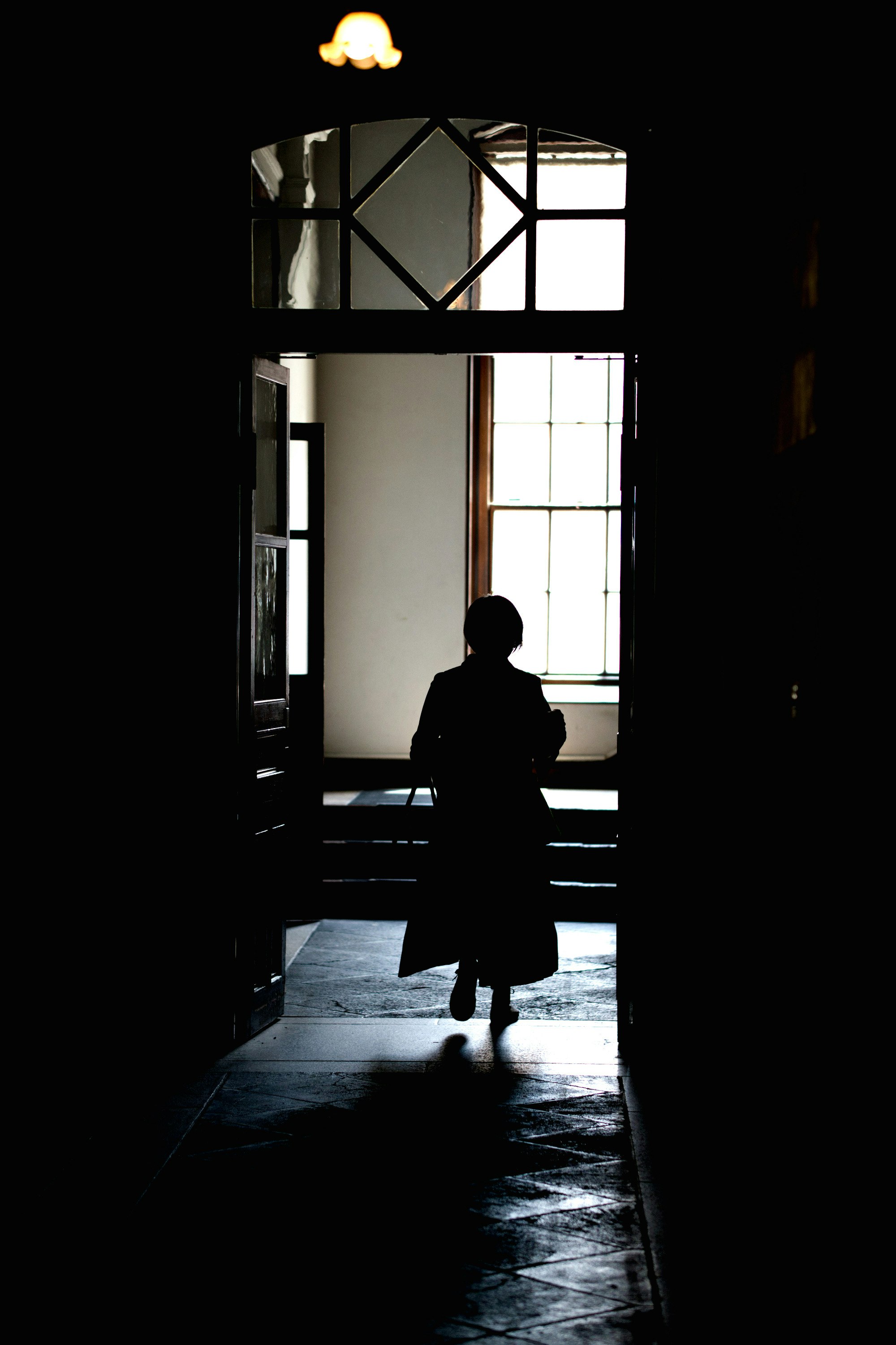 京都文化博物館別館の中庭を差し込む窓光と人物のシルエット