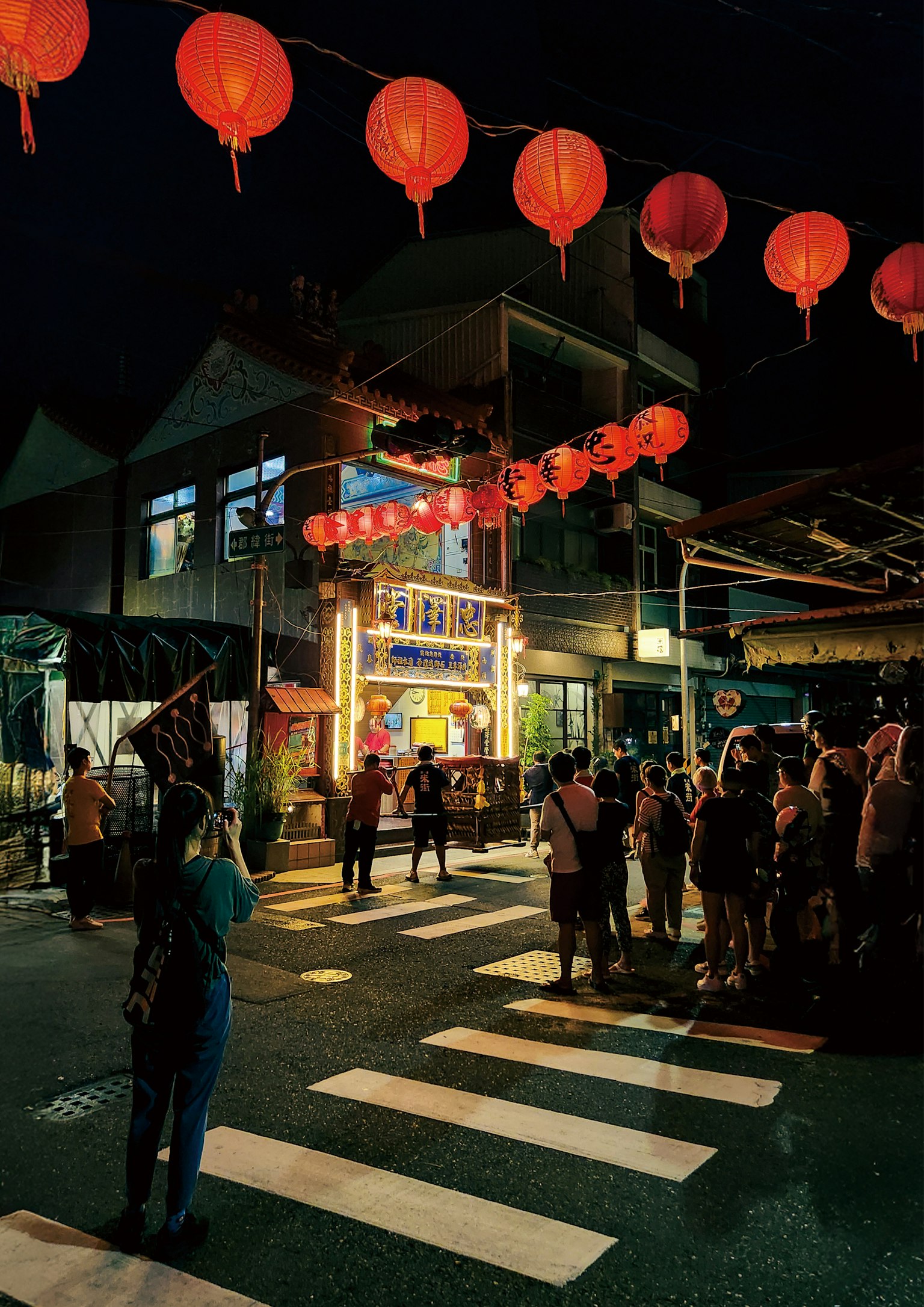 Multitud reunida en una calle adornada con faroles rojos por la noche