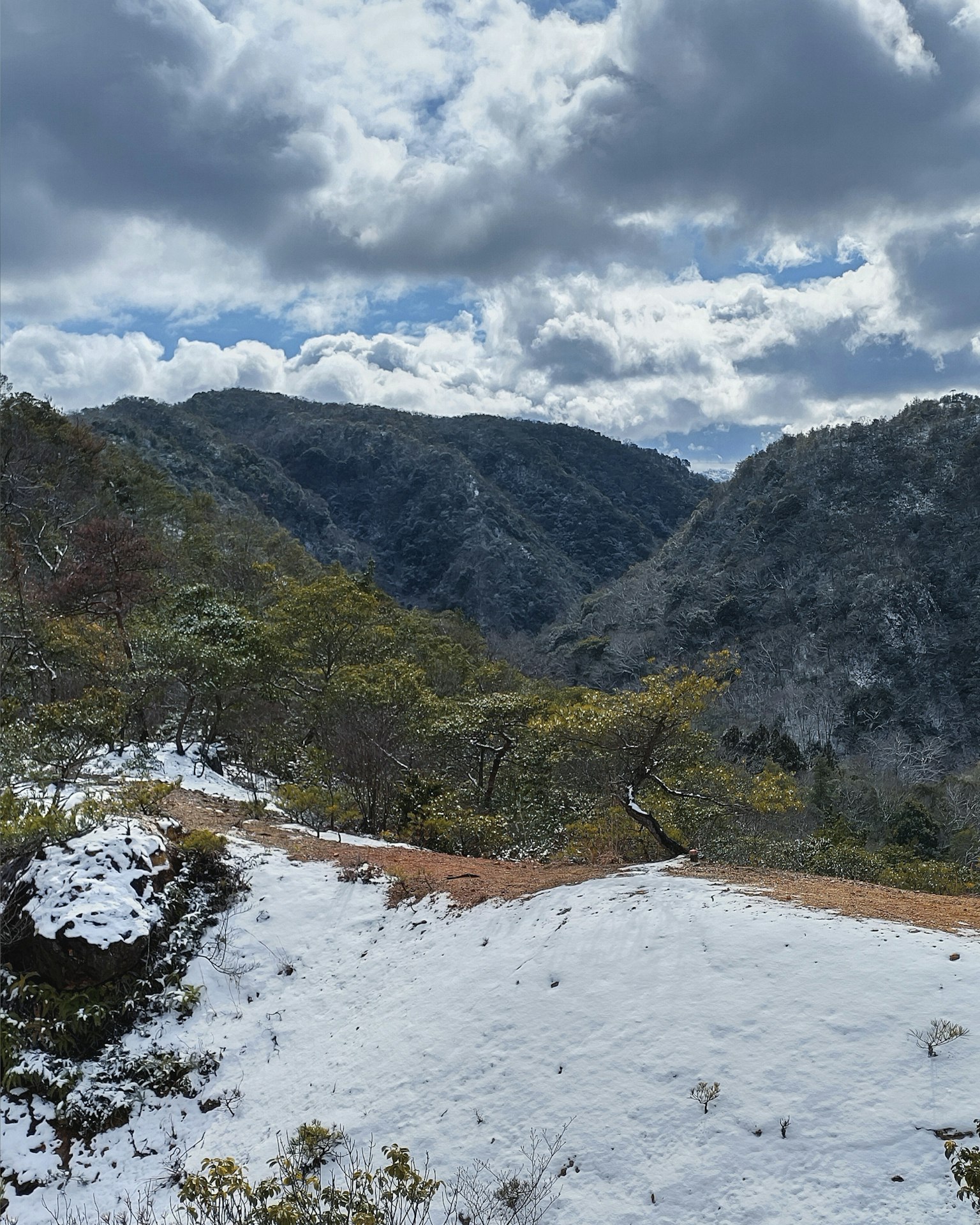 被雪覆盖的山路与蓝天和云朵的背景
