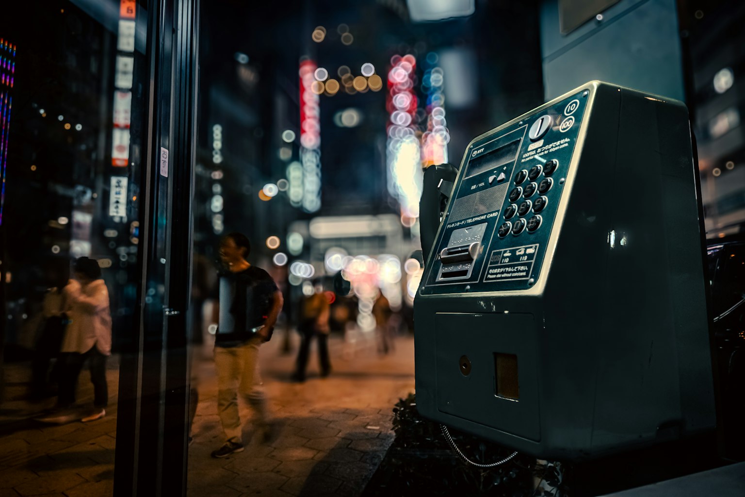 Photo of an old payphone in a vibrant city at night