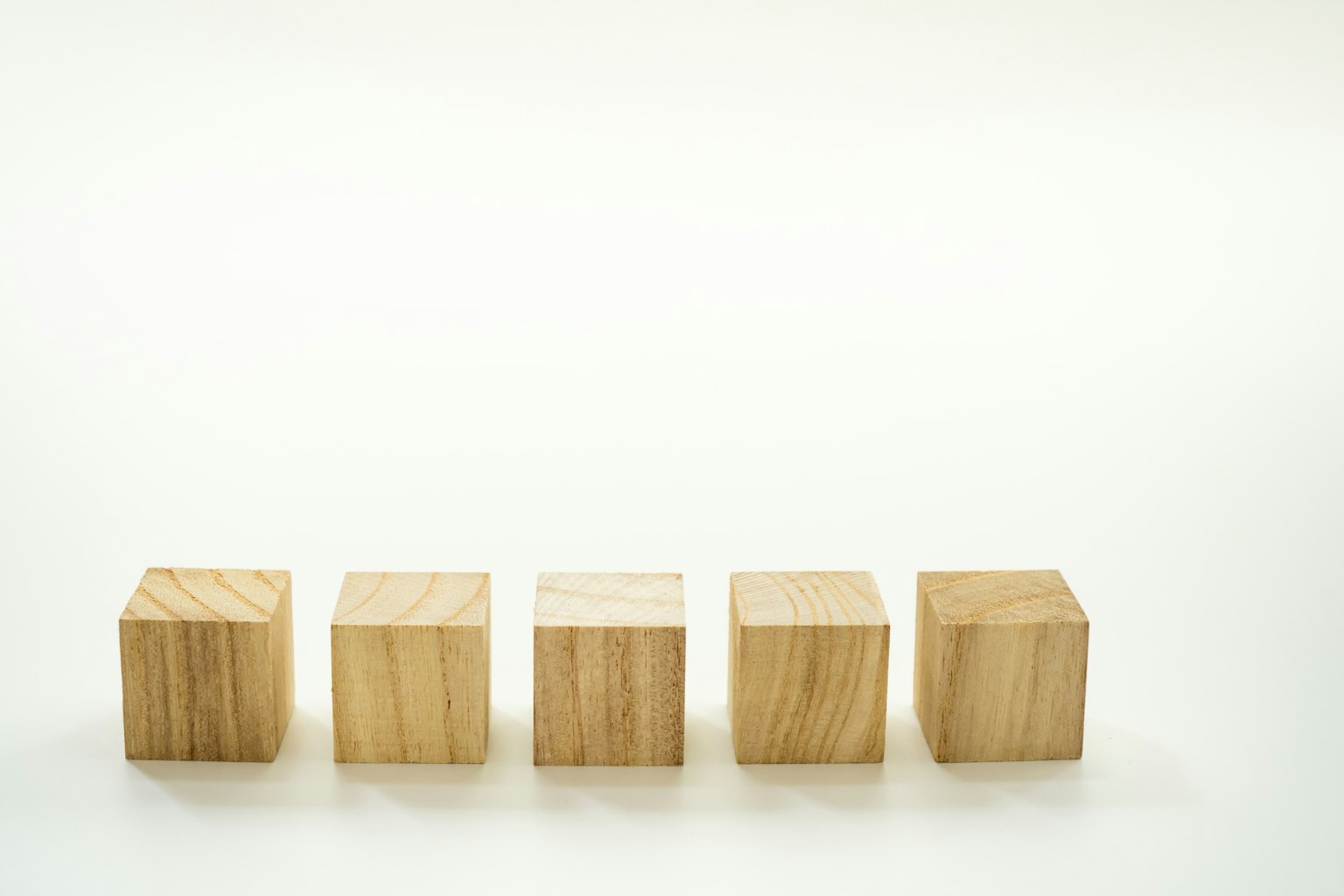 Una fila de cubos de madera dispuestos ordenadamente sobre un fondo claro
