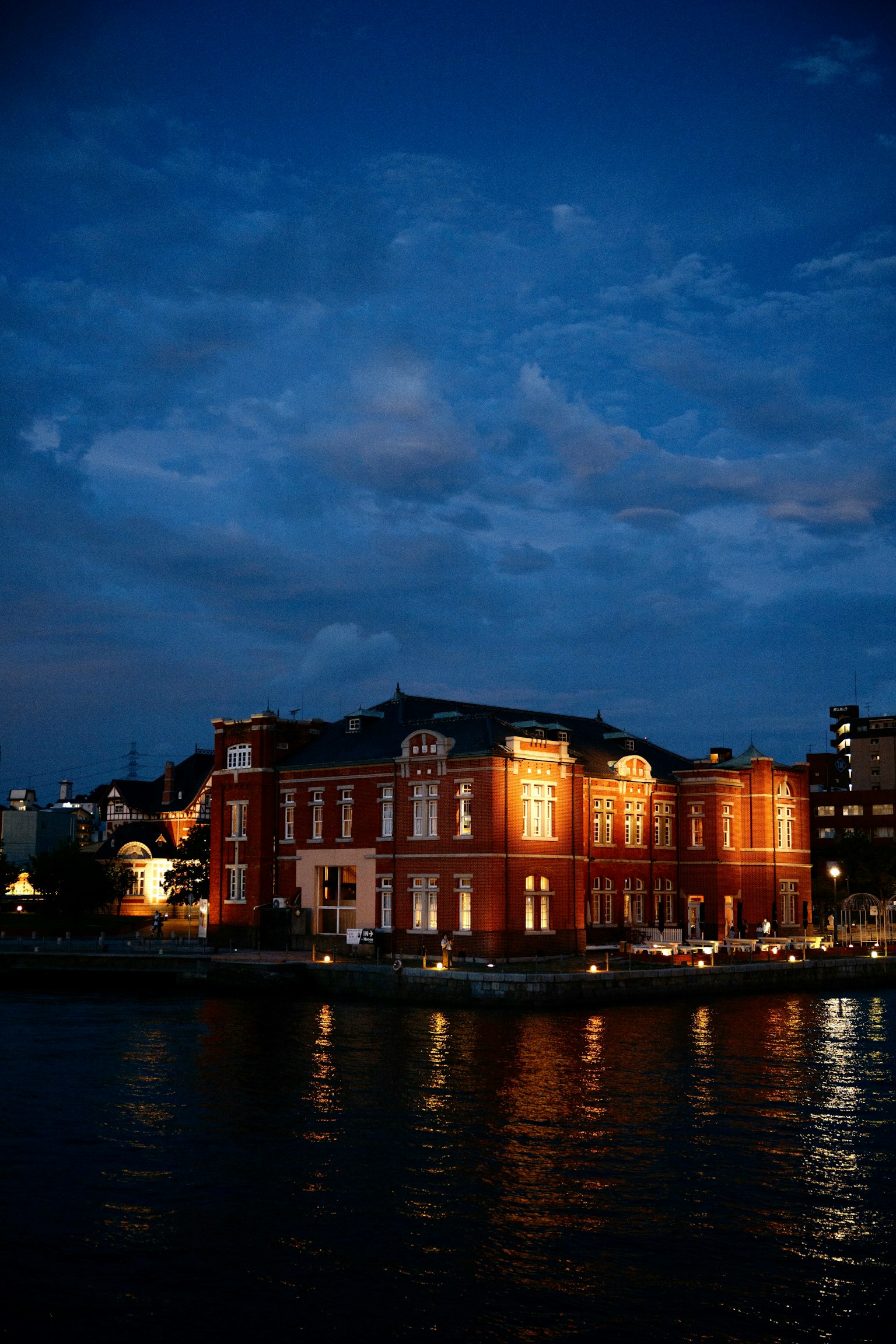 Bâtiment en brique rouge illuminé au crépuscule près de l'eau