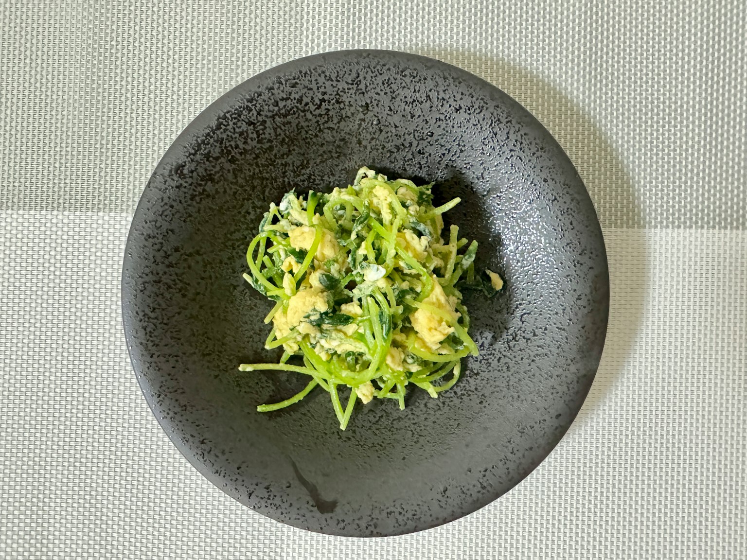 Insalata di pasta verde servita in un piatto nero