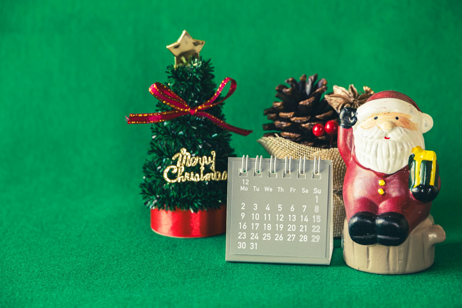 Un piccolo albero di Natale decorato una statuetta di Babbo Natale e un calendario disposti insieme