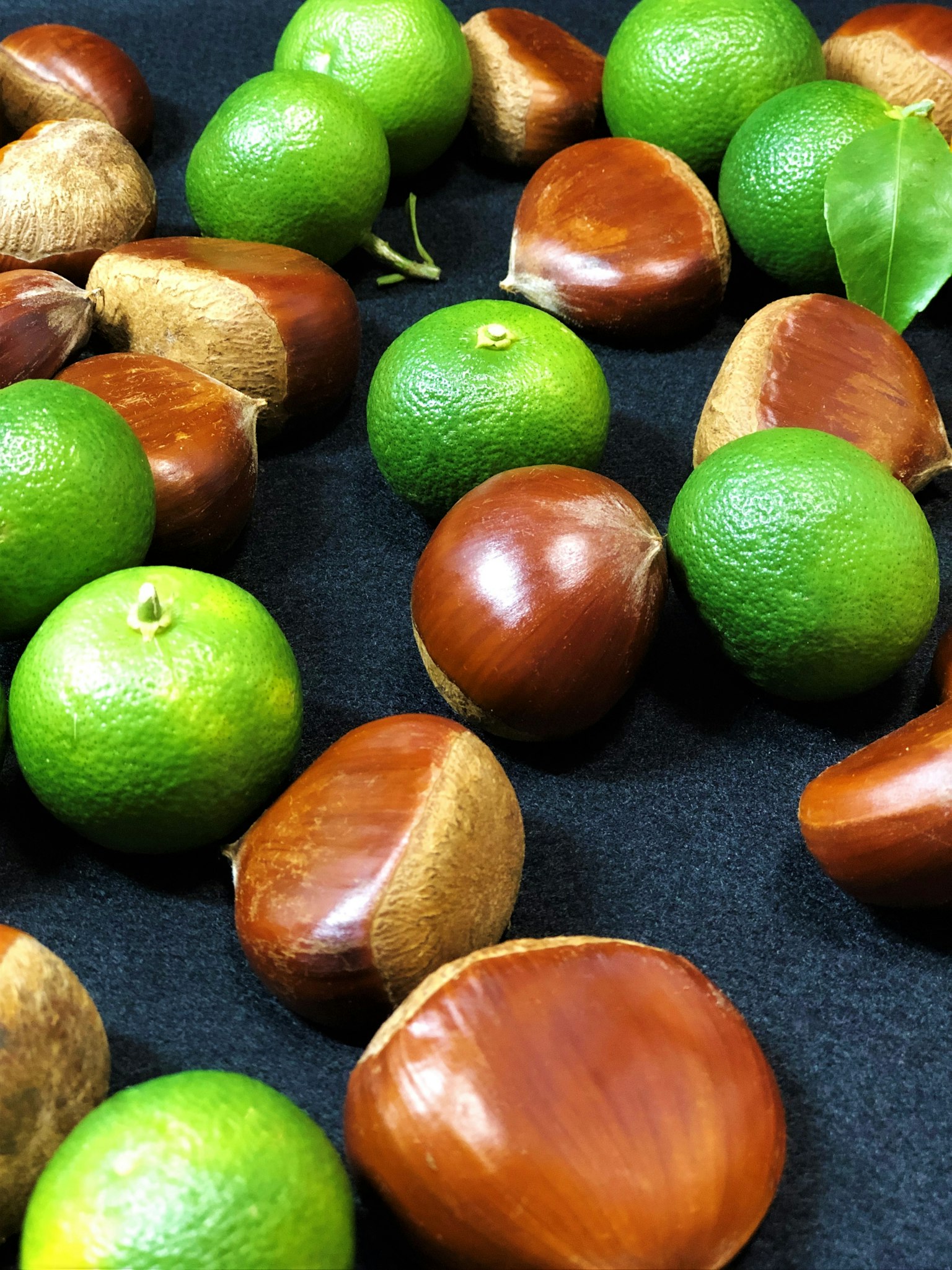 Un mélange de limes vertes et de châtaignes brunes sur une surface sombre