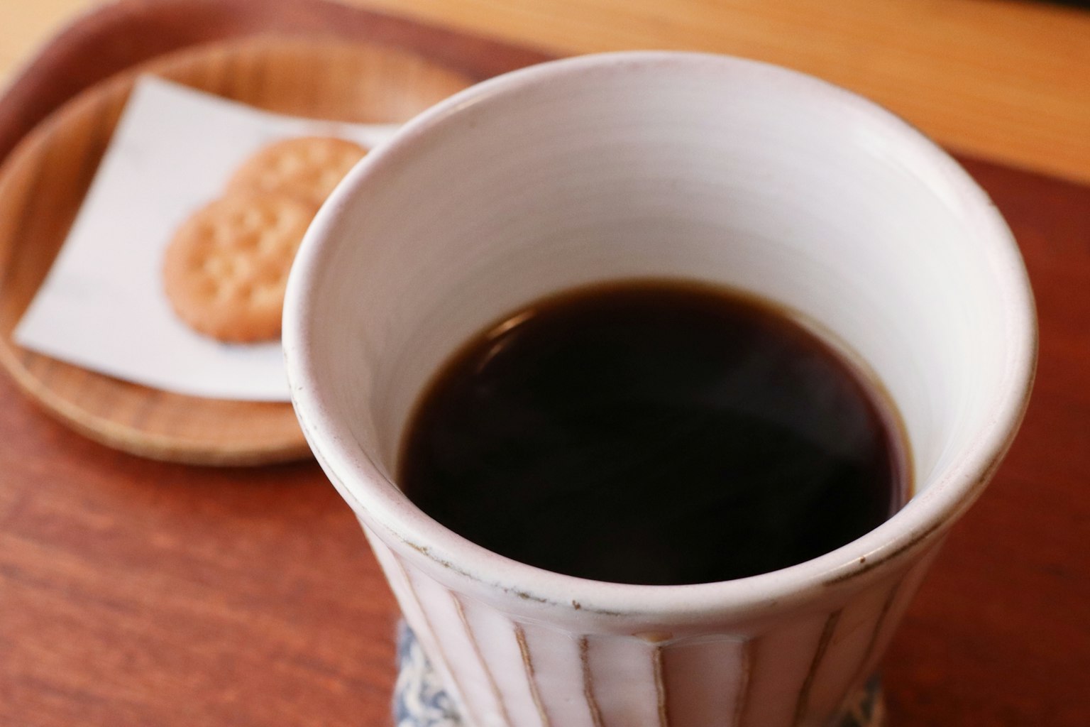 一幅溫馨的圖片，展示了一杯黑咖啡和木托盤上的餅乾