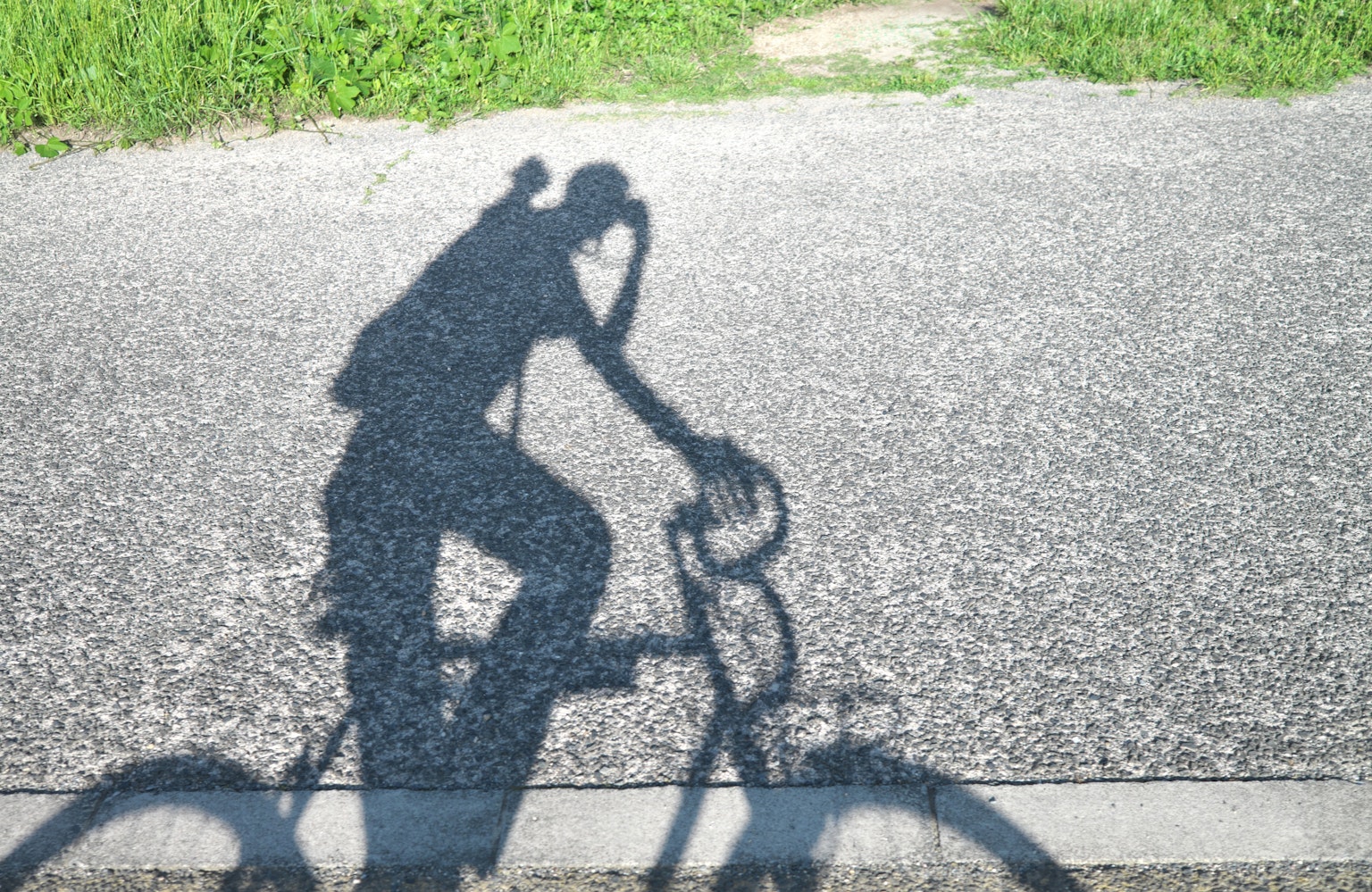 Bóng của một người đang đi xe đạp trên vỉa hè