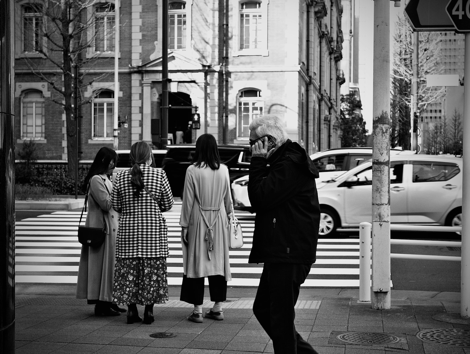 ภาพถนนขาวดำที่มีผู้หญิงรอข้ามถนนและผู้เดินผ่าน